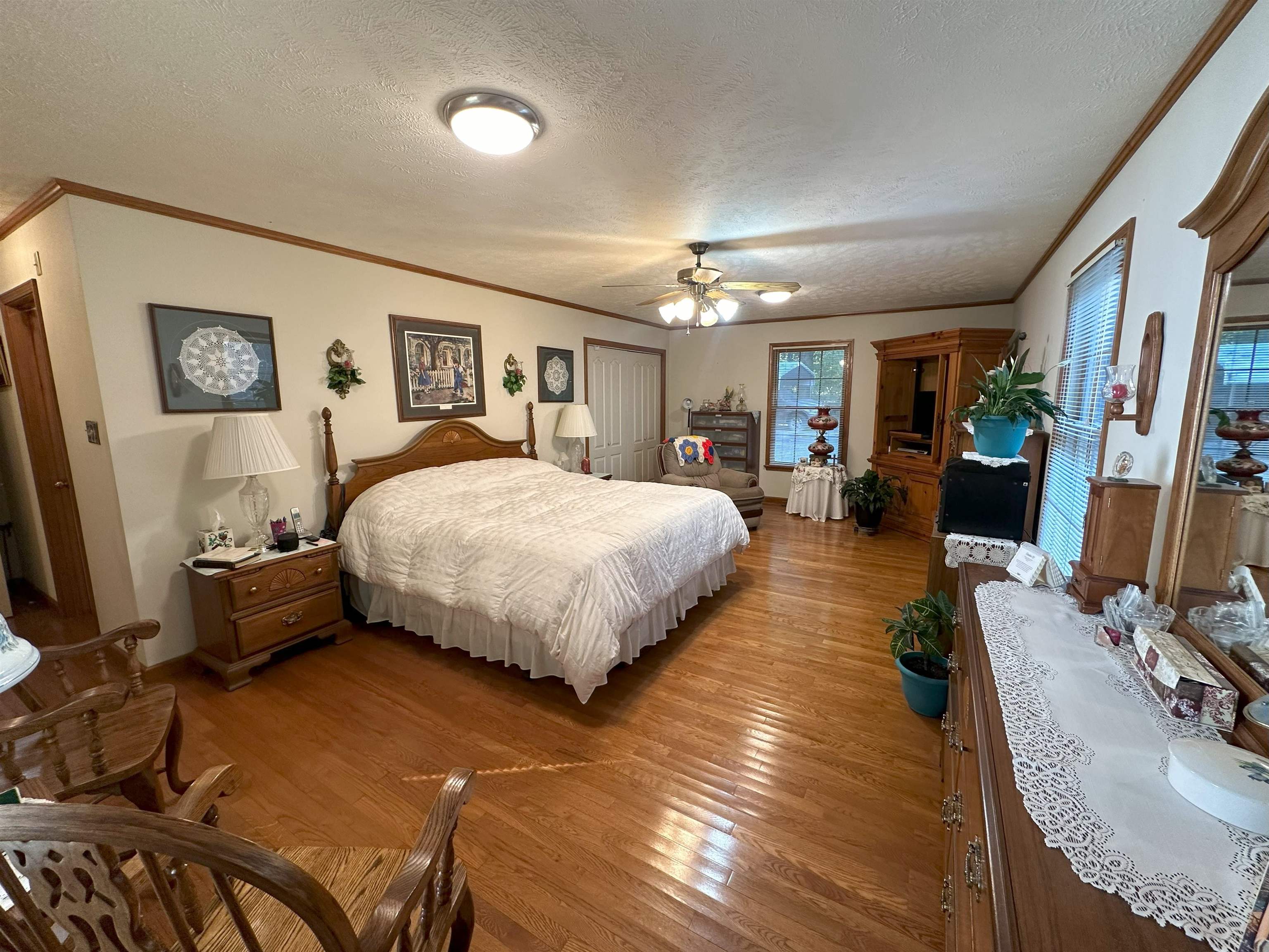 Bedroom with ceiling fan, crown molding, a textured ceiling, and light wood-type flooring