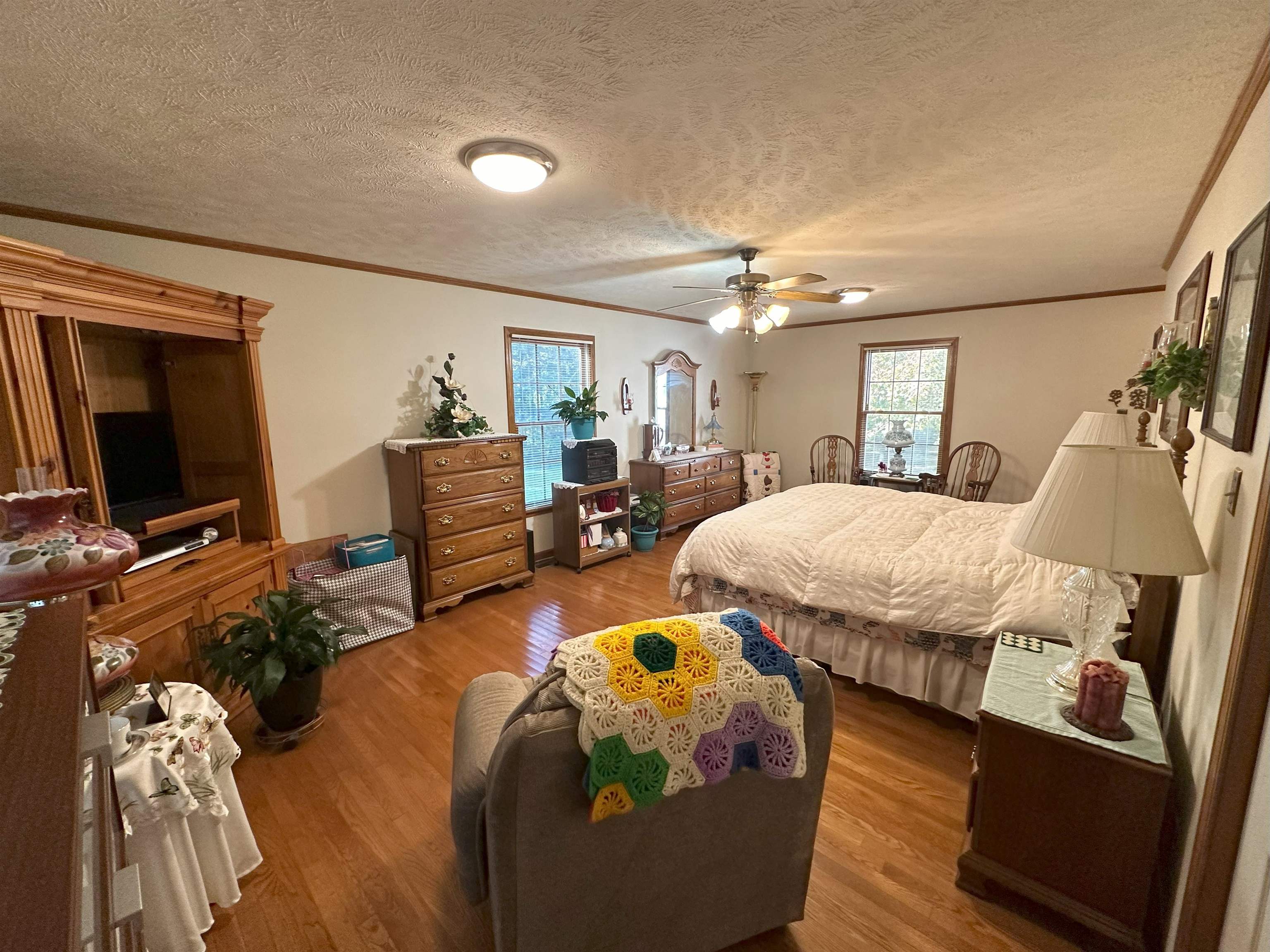 Bedroom with a textured ceiling, hardwood / wood-style flooring, and ceiling fan