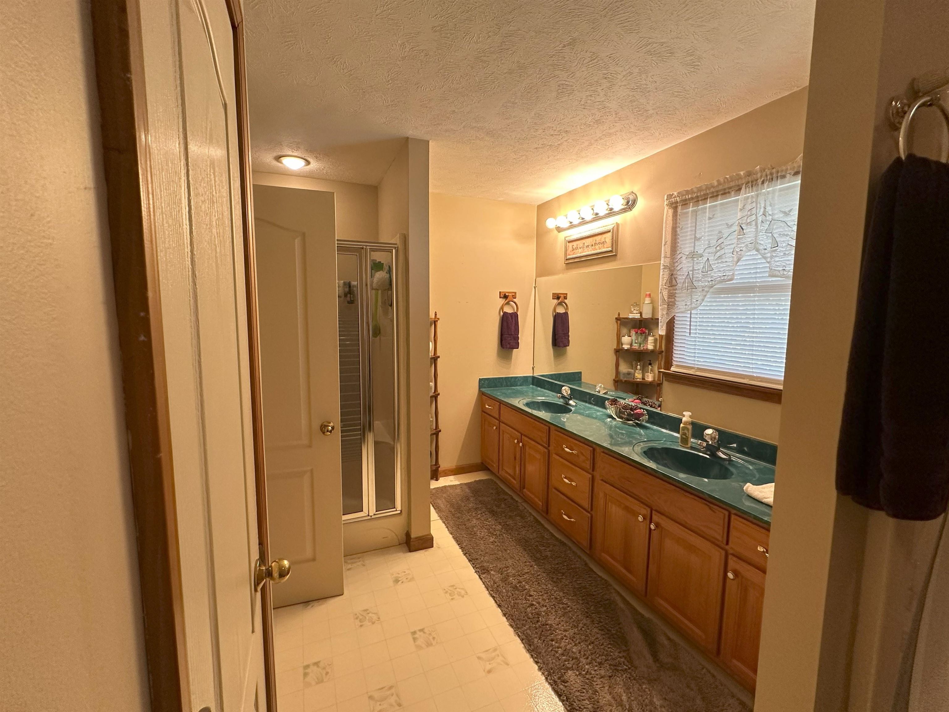 Bathroom featuring vanity, walk in shower, and a textured ceiling
