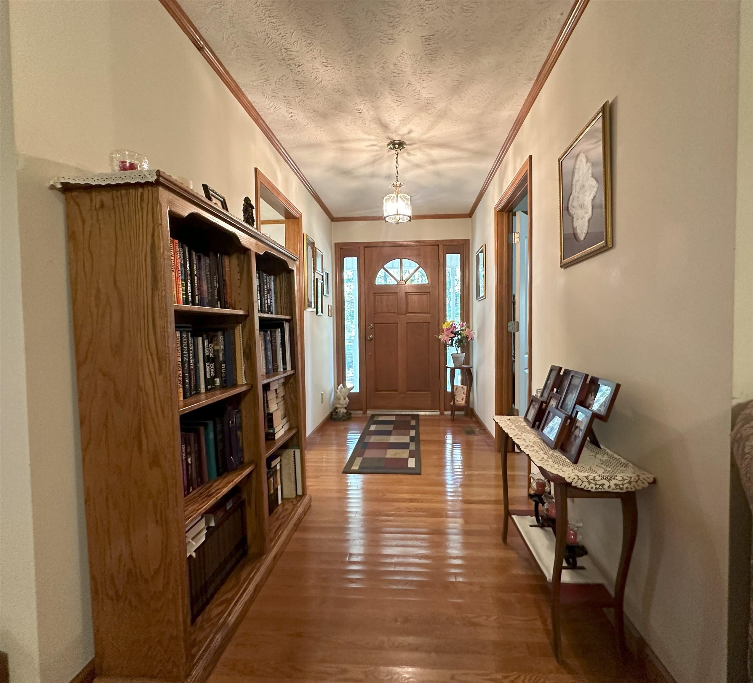 Foyer entrance featuring ornamental molding, a textured ceiling, and dark wood-type flooring