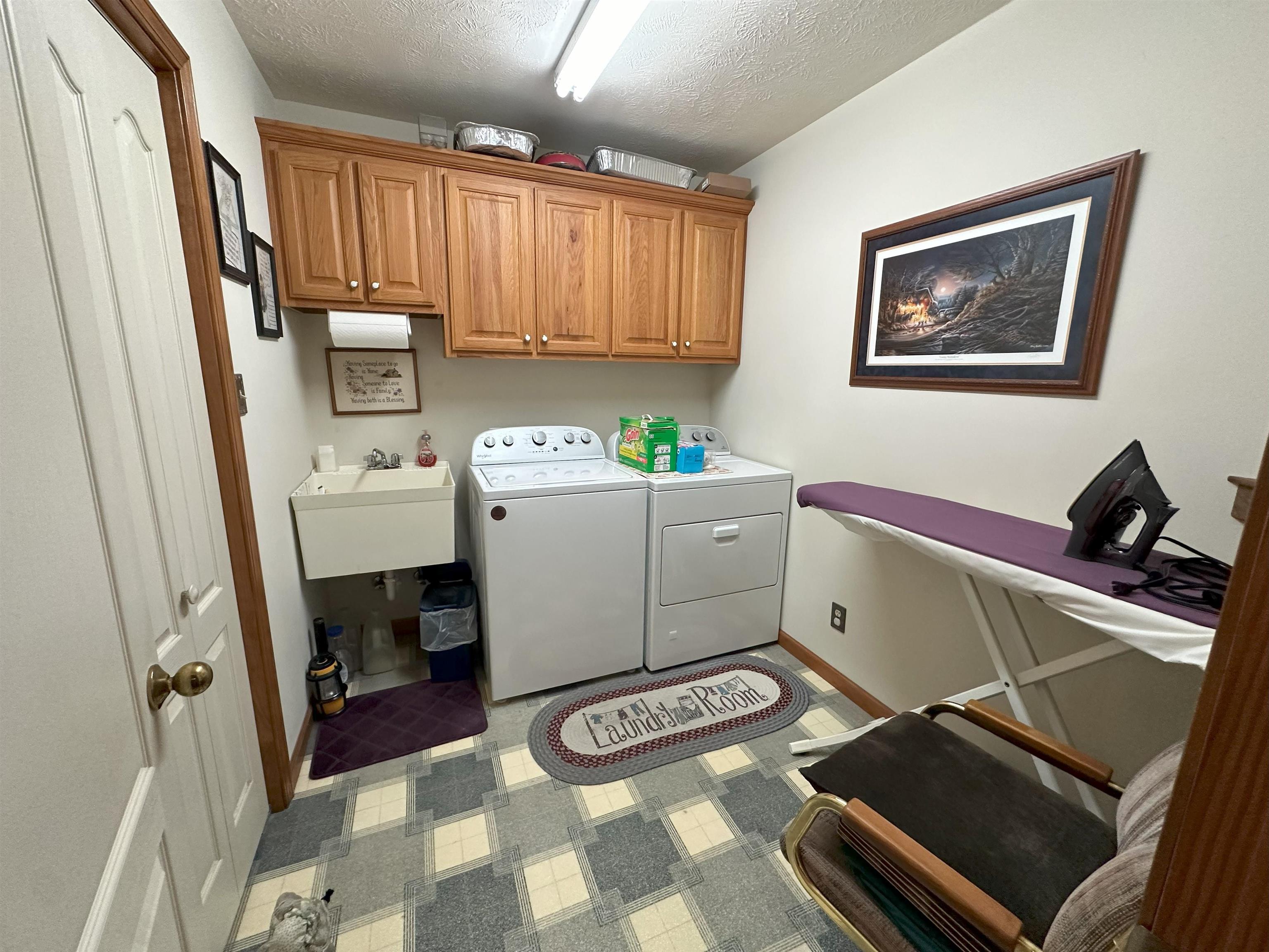 Laundry area with sink, a textured ceiling, cabinets, and separate washer and dryer