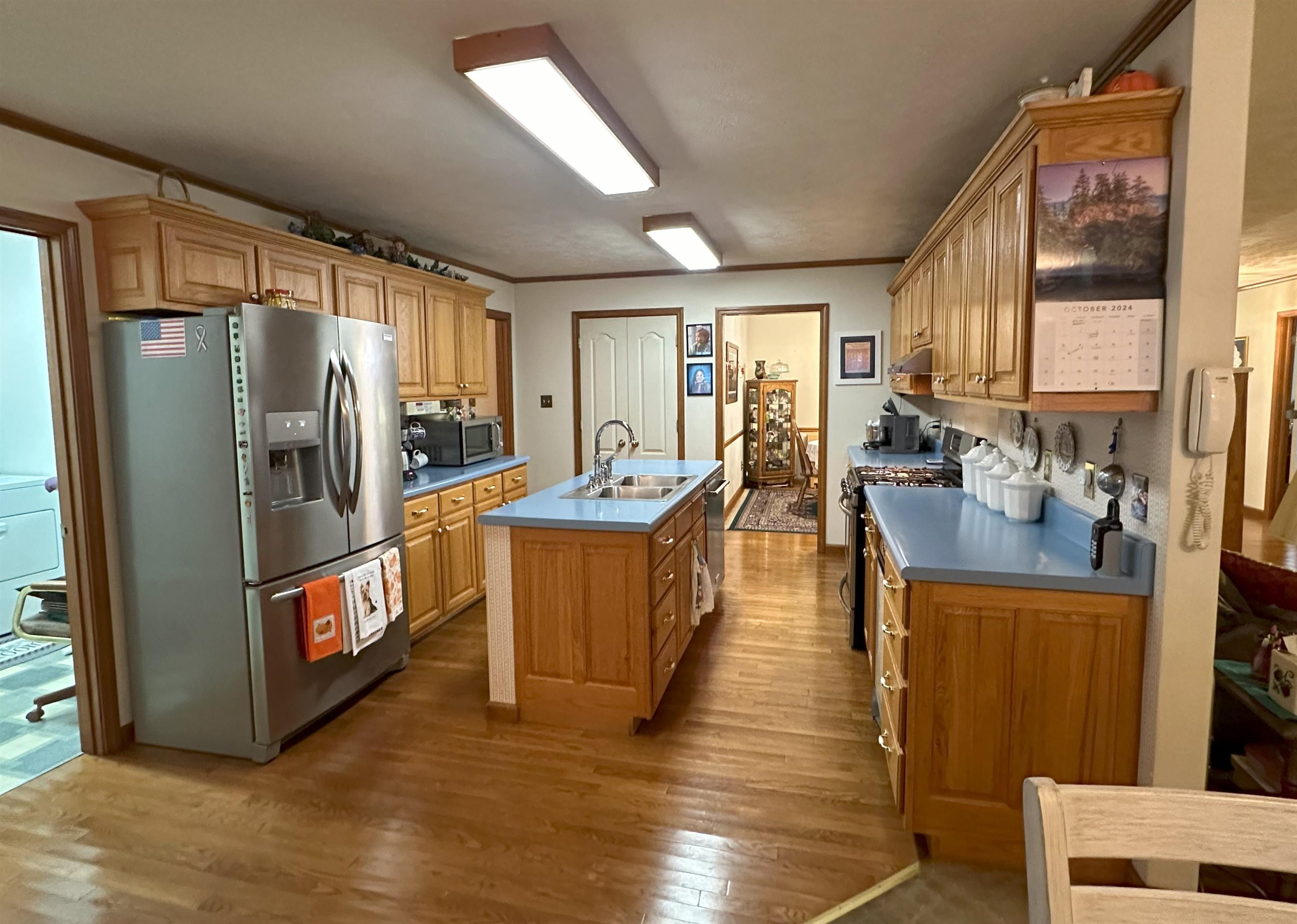 Kitchen featuring wood-type flooring, sink, an island with sink, stainless steel appliances, and ornamental molding