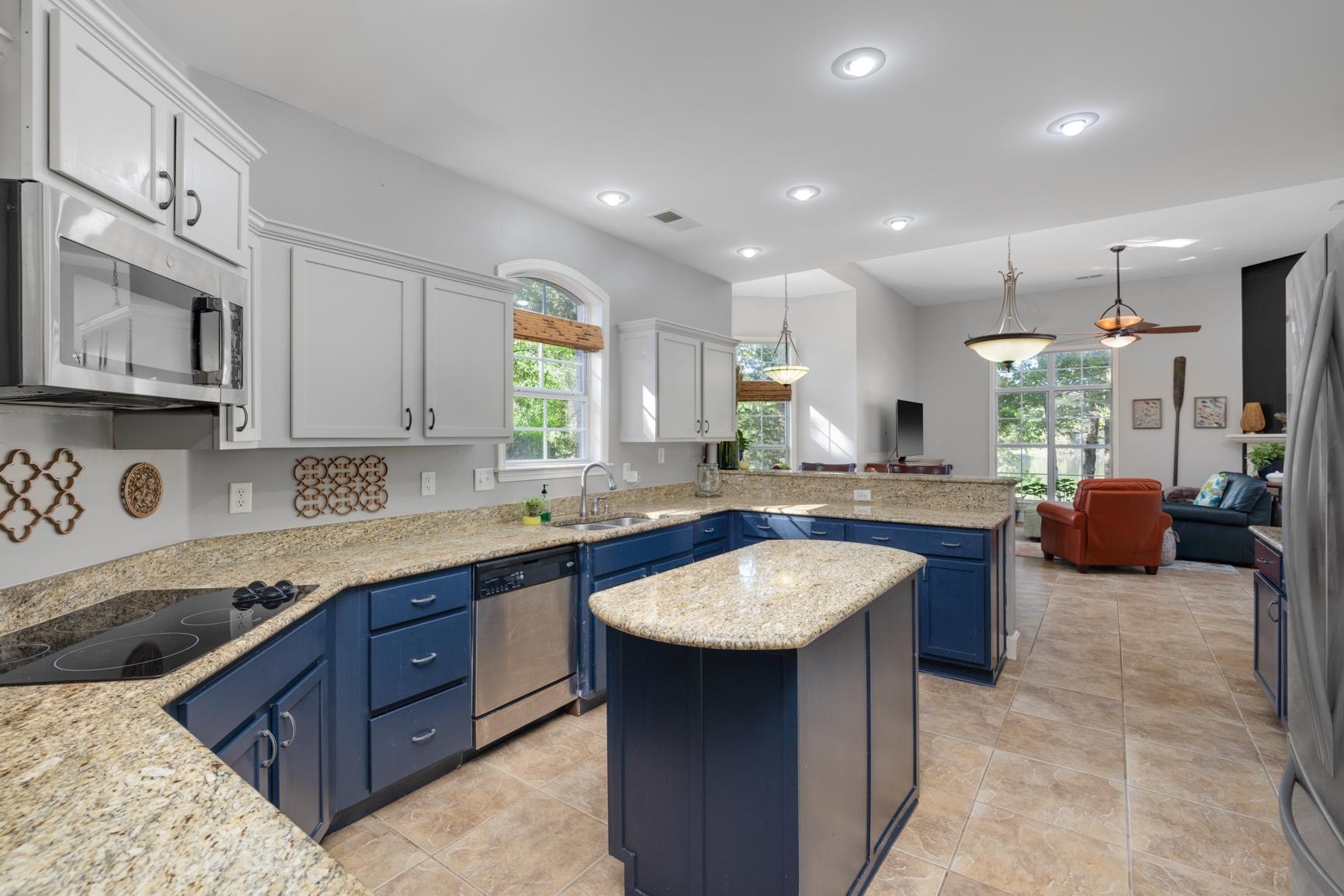 Kitchen featuring white cabinets, a kitchen island, appliances with stainless steel finishes, a wealth of natural light, and blue cabinets