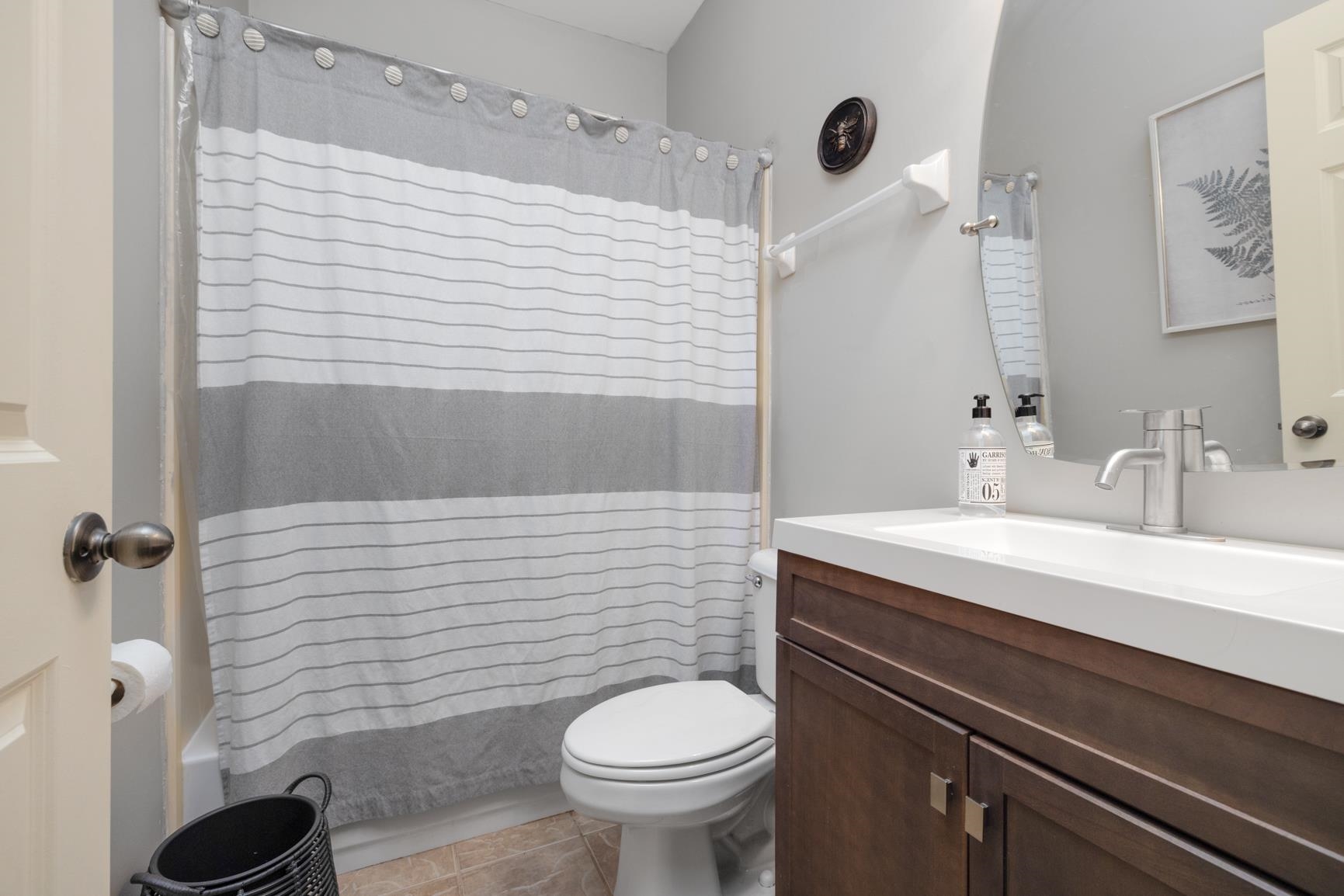 Full bathroom with vanity, shower / bath combination with curtain, toilet, and tile patterned floors