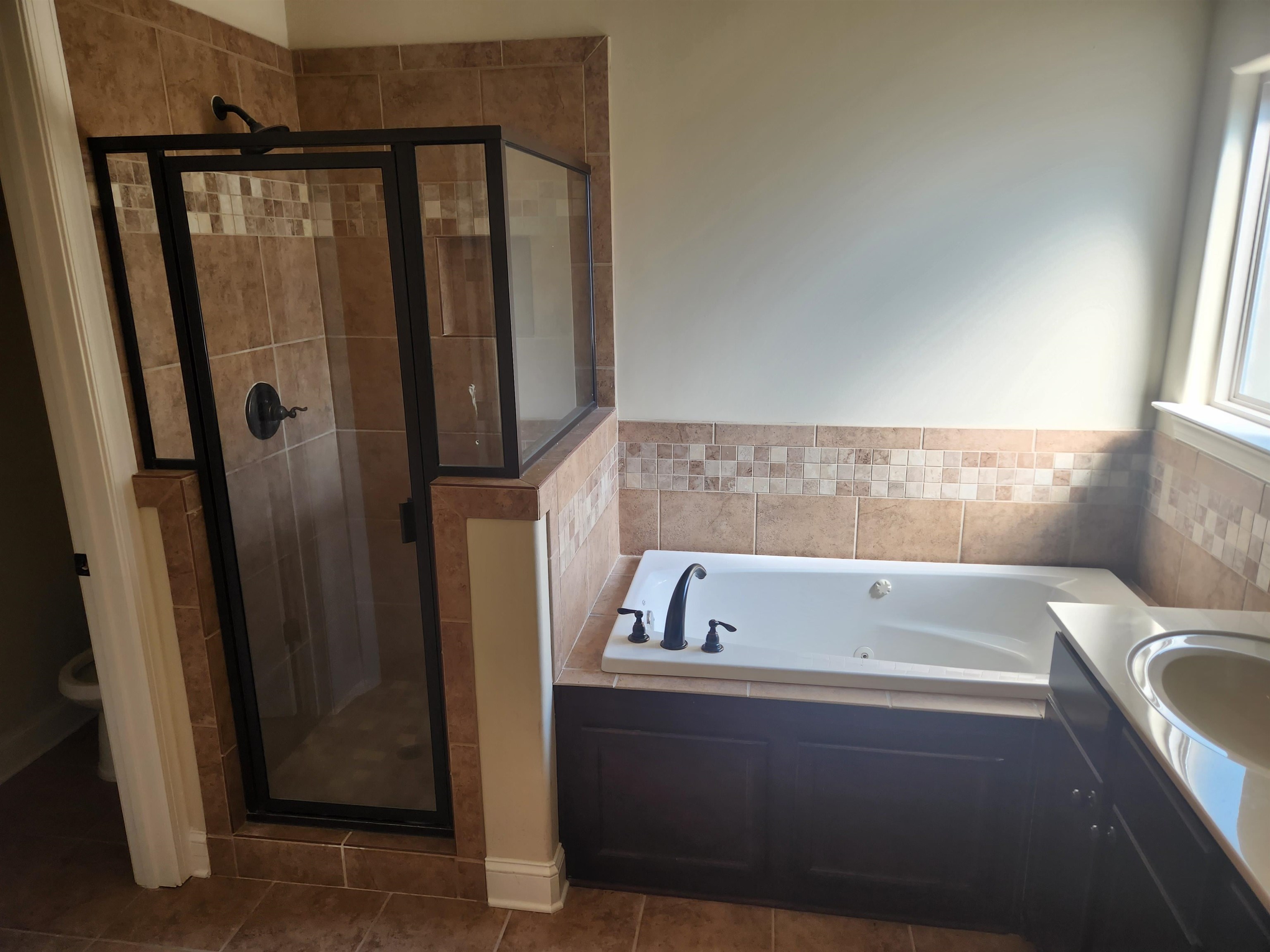 Bathroom featuring toilet, tile patterned floors, and shower with separate bathtub