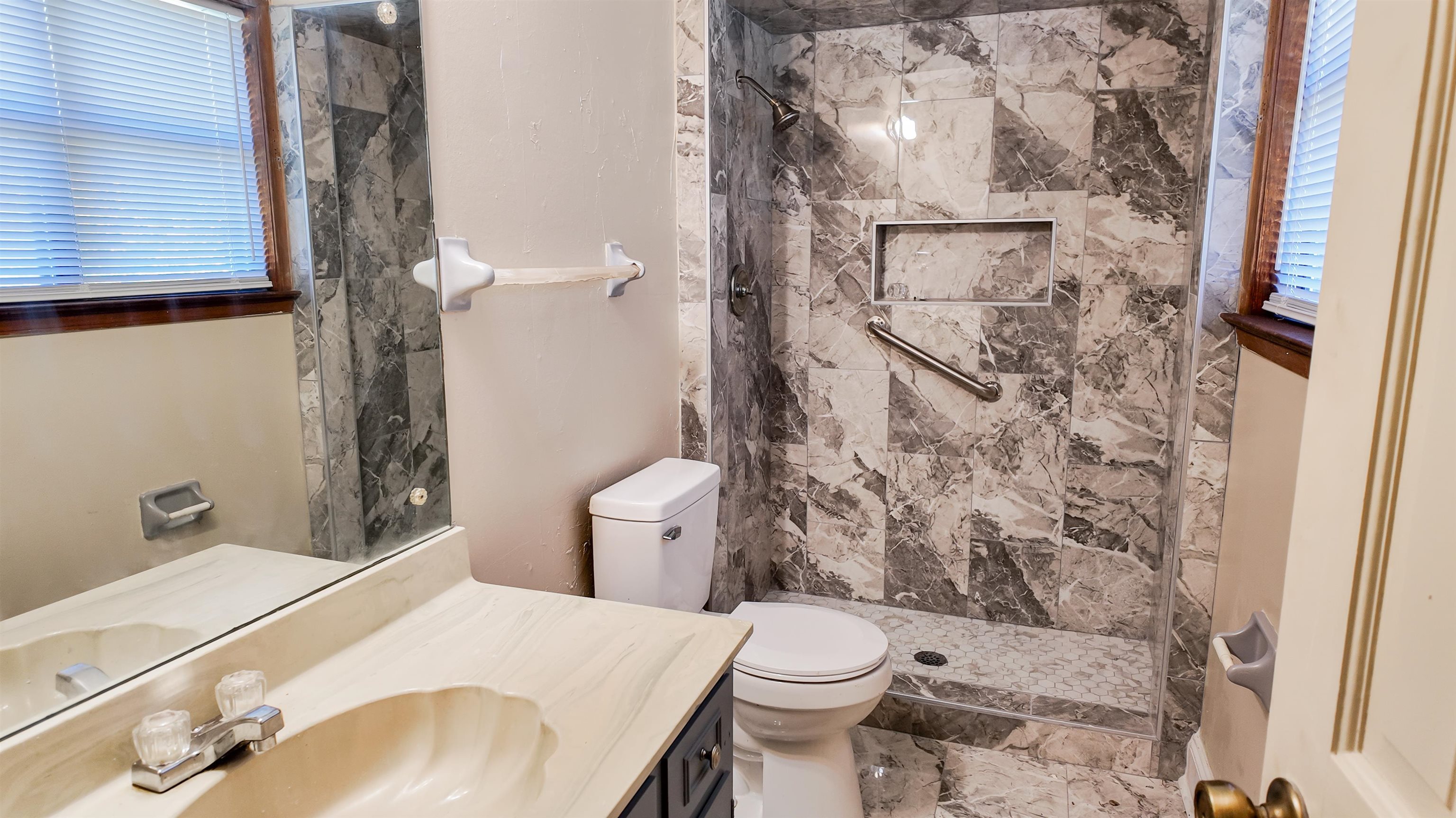 Bathroom featuring toilet, vanity, and a tile shower