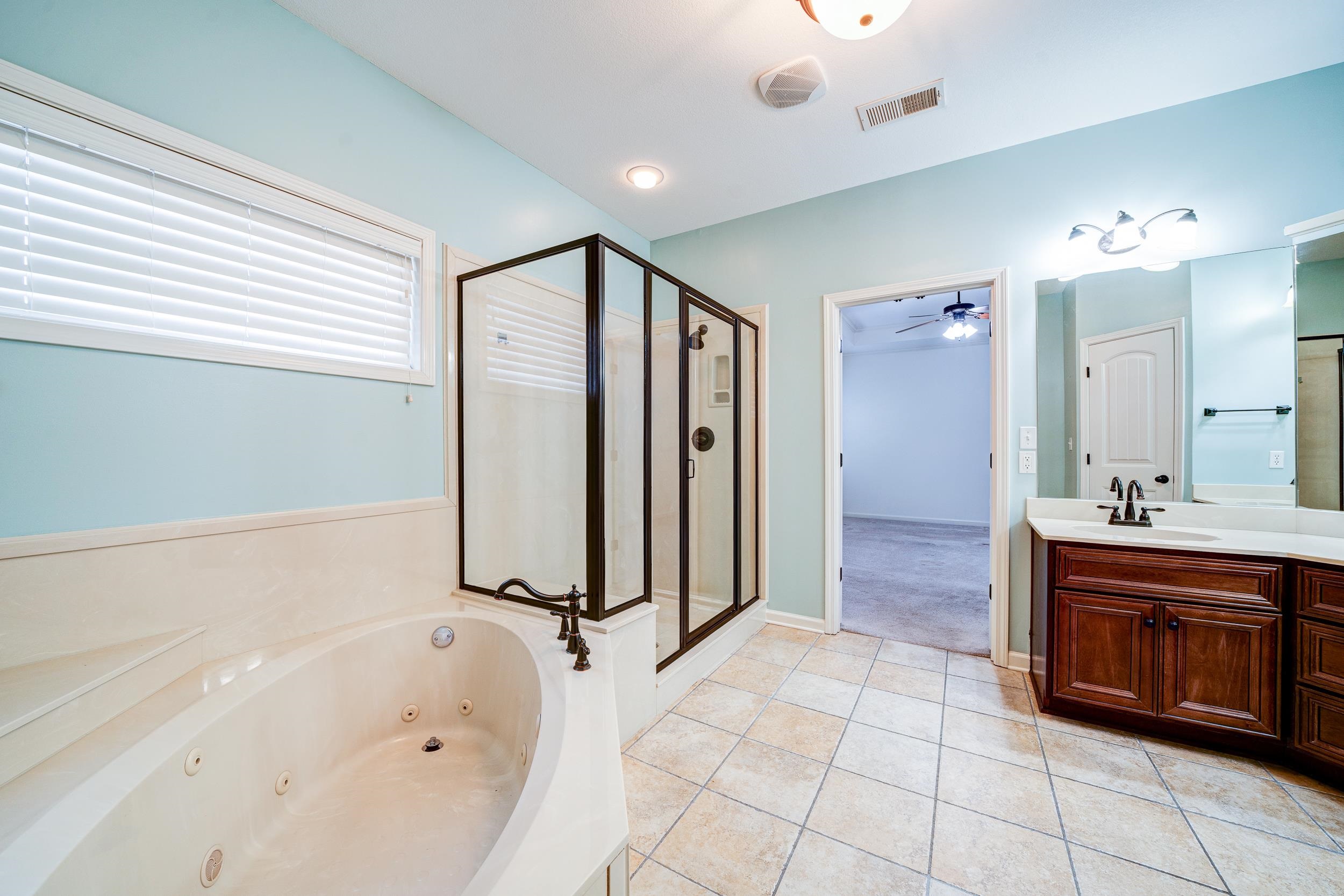 Bathroom featuring vanity, separate shower and tub, ceiling fan, and tile patterned floors