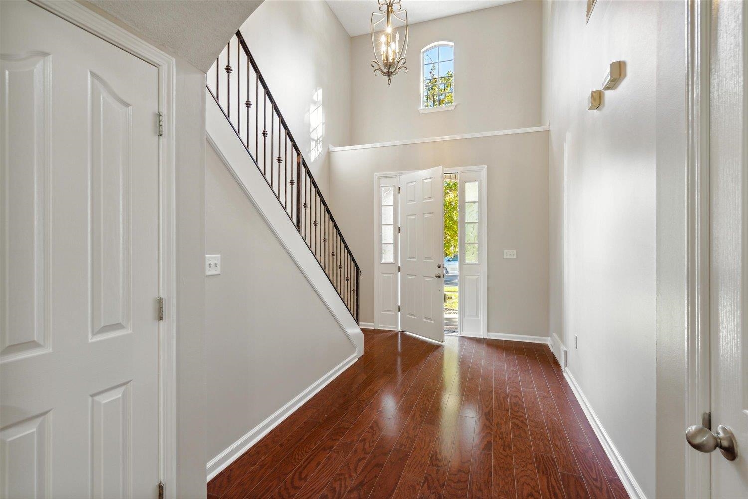 Foyer entrance with a high ceiling, an inviting chandelier, a wealth of natural light, and dark hardwood / wood-style floors