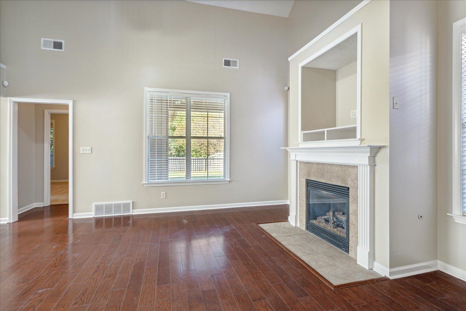 Unfurnished living room with high vaulted ceiling, dark hardwood / wood-style flooring, and a tile fireplace