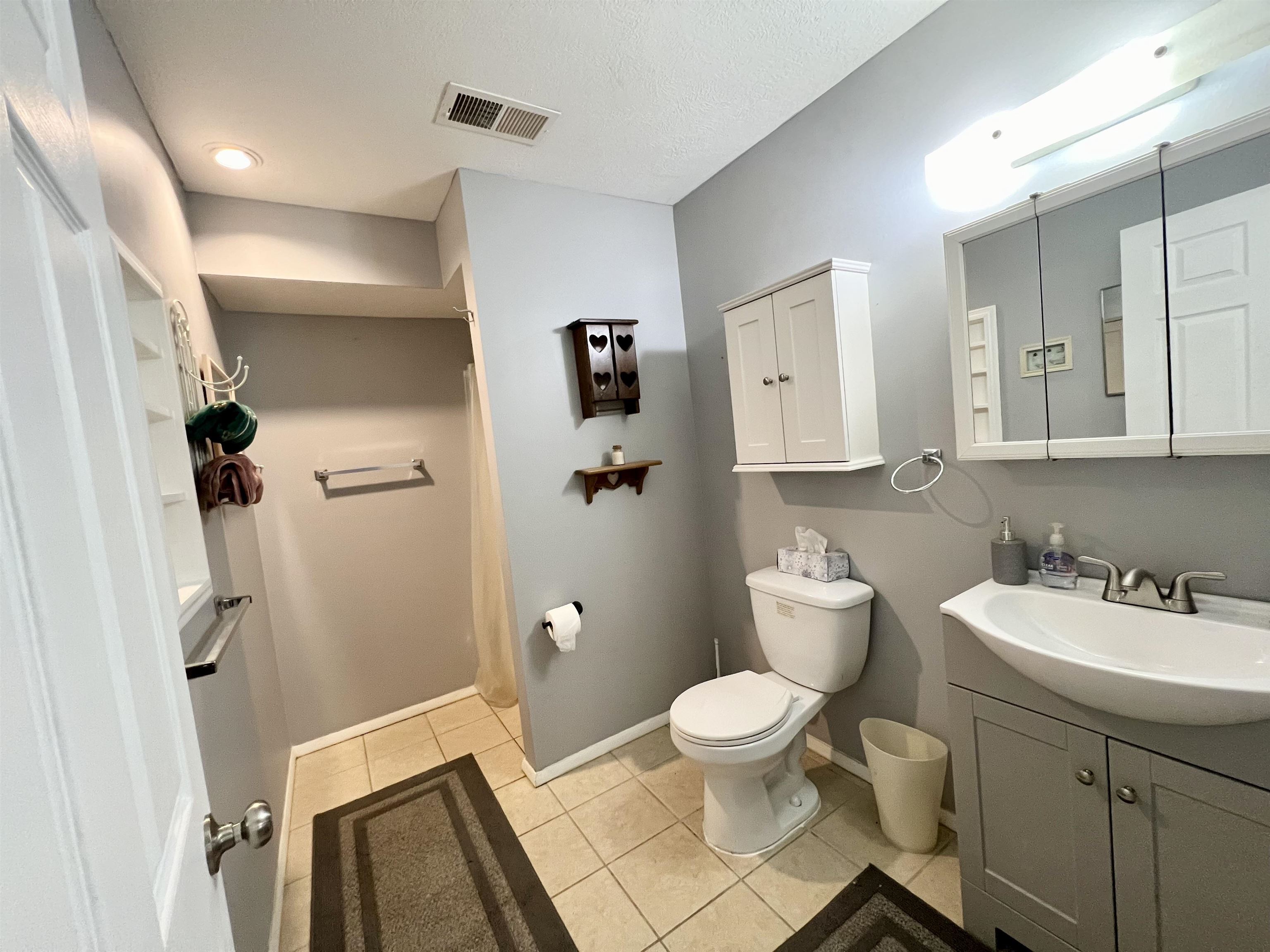 Bathroom with toilet, a textured ceiling, vanity, and tile patterned flooring