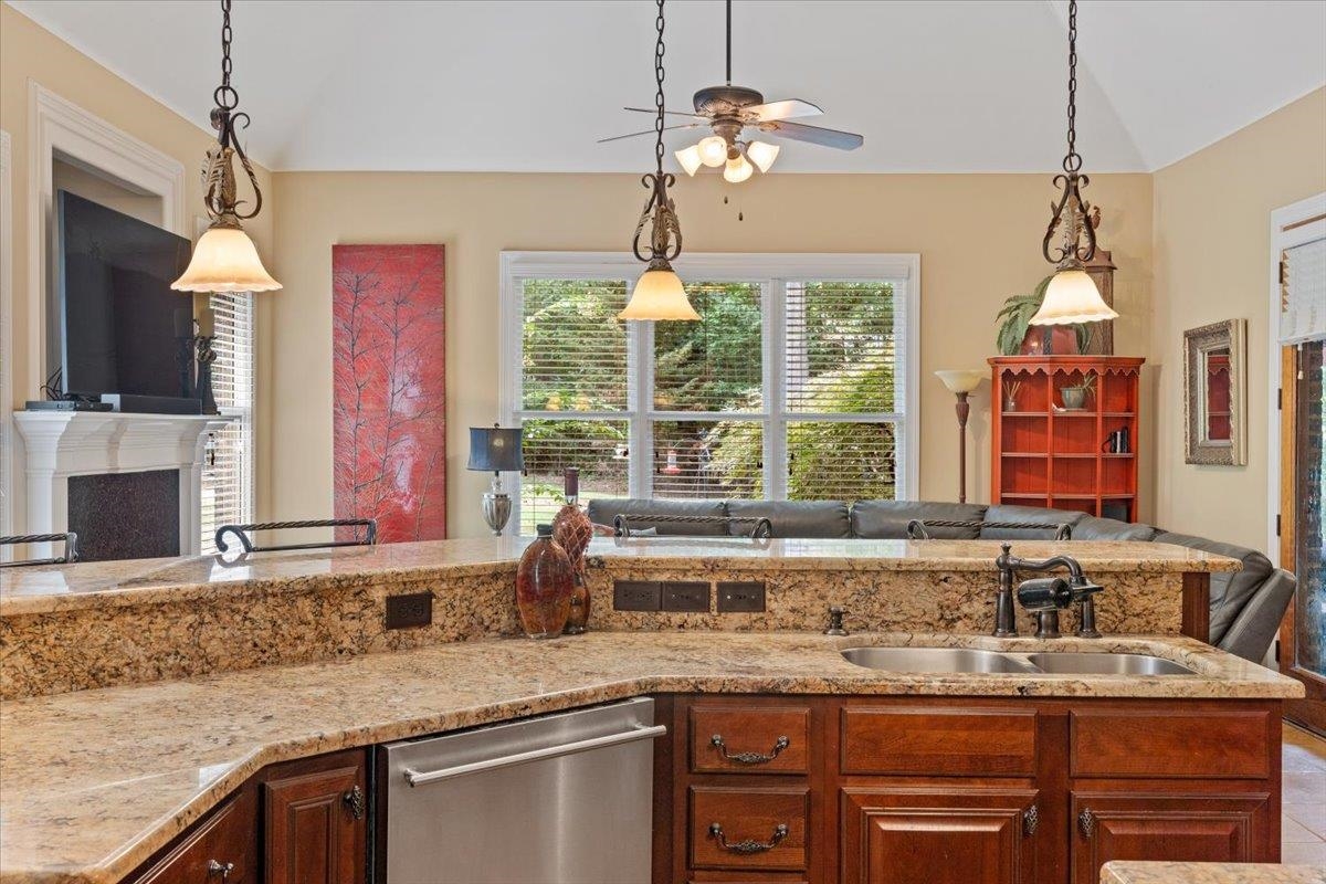 Kitchen featuring sink, hanging light fixtures, lofted ceiling, and dishwasher