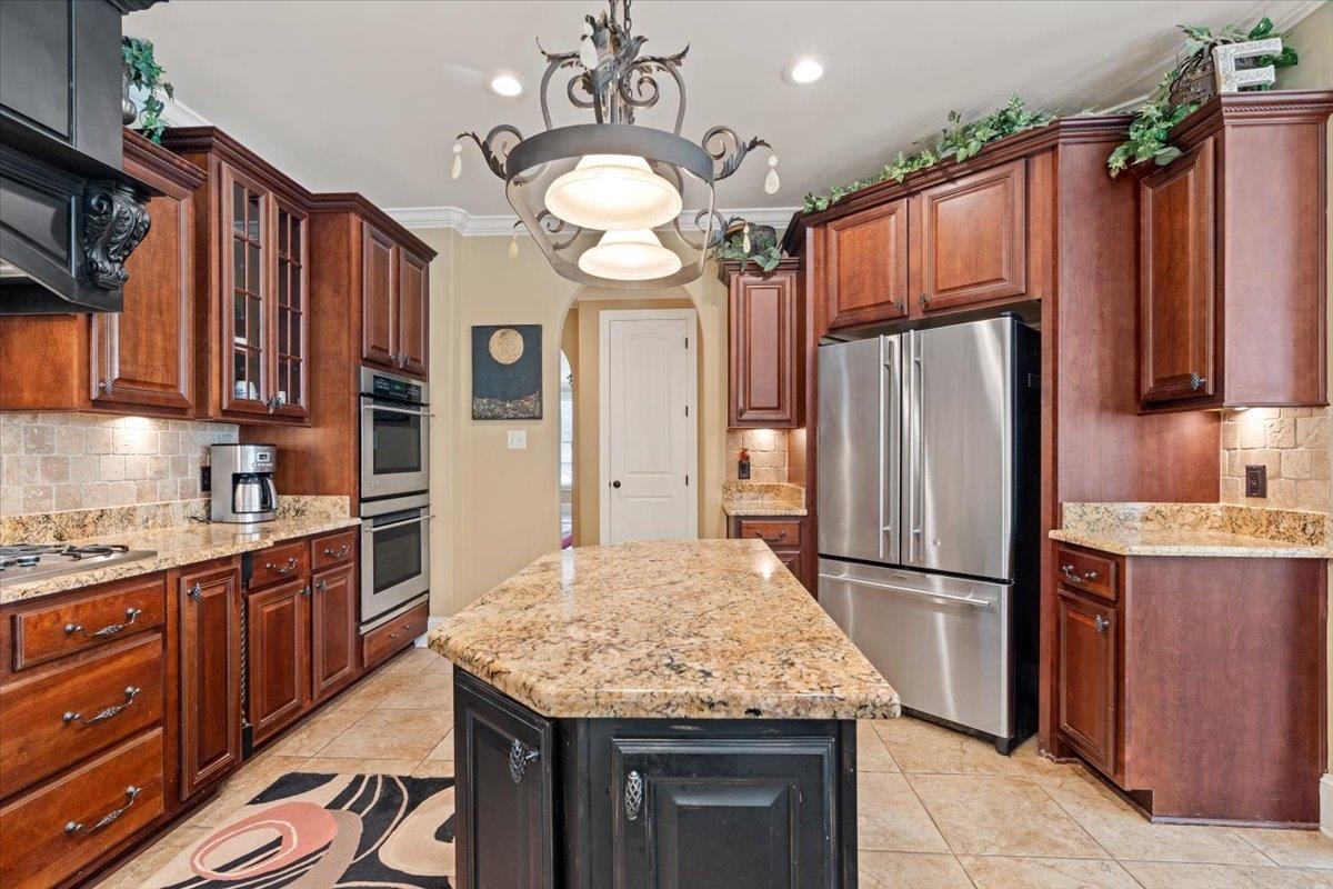 Kitchen featuring crown molding, stainless steel appliances, decorative backsplash, and a center island