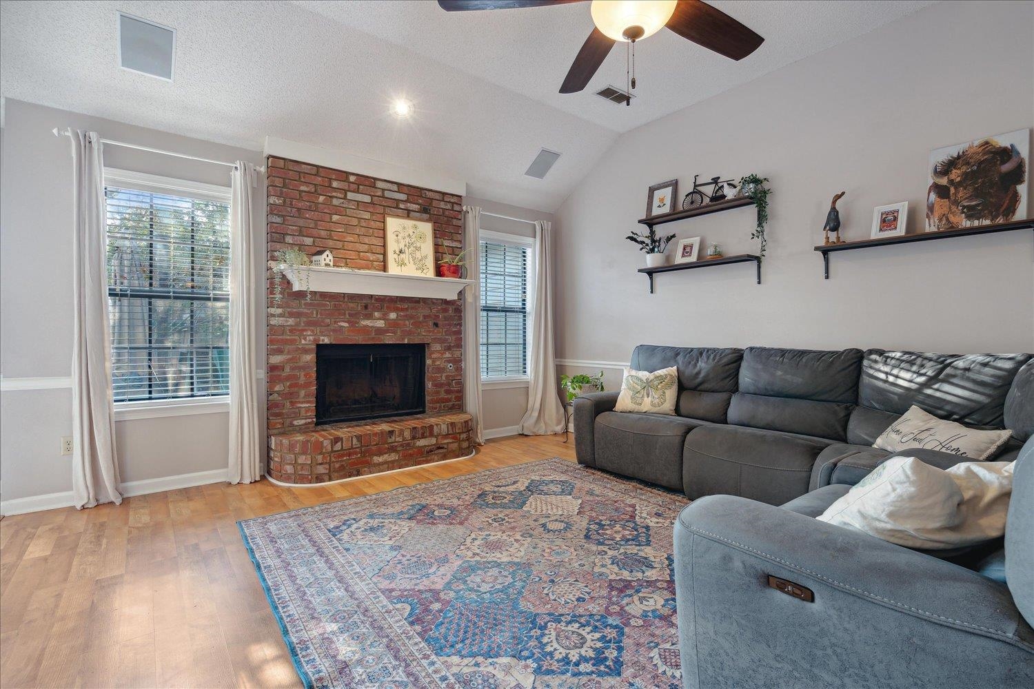 Living room featuring lofted ceiling, a fireplace, light wood-type flooring, and a wealth of natural light