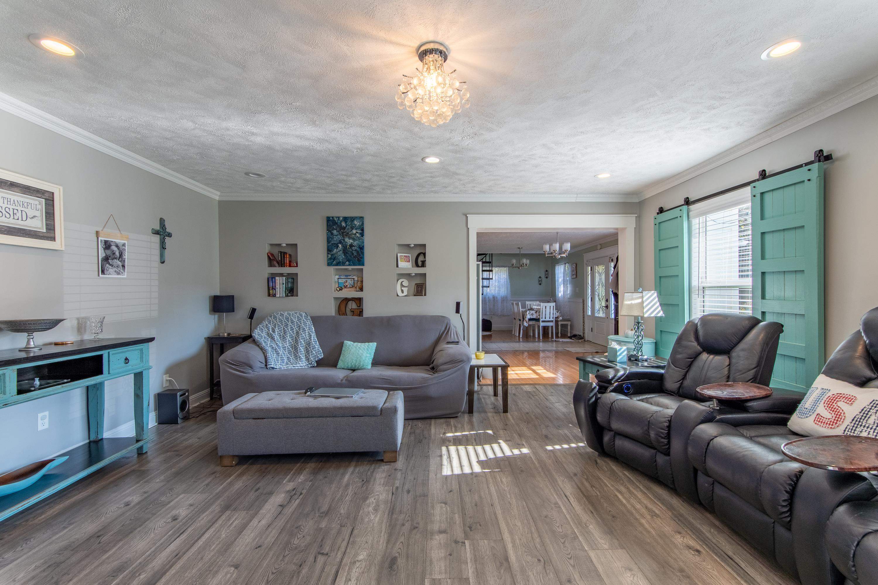 Living room with a notable chandelier, hardwood / wood-style floors, and a barn door