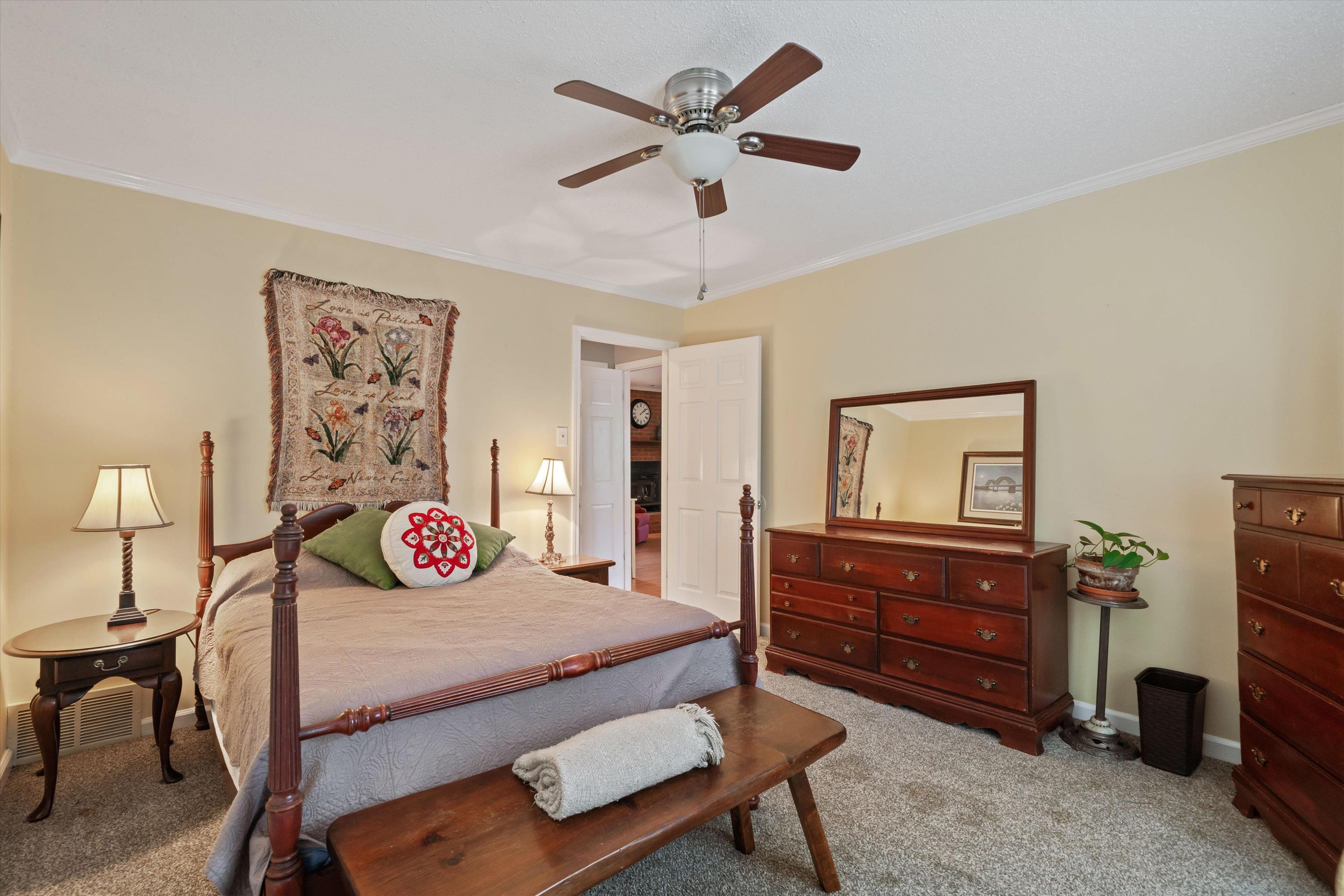 Carpeted bedroom with ceiling fan and crown molding