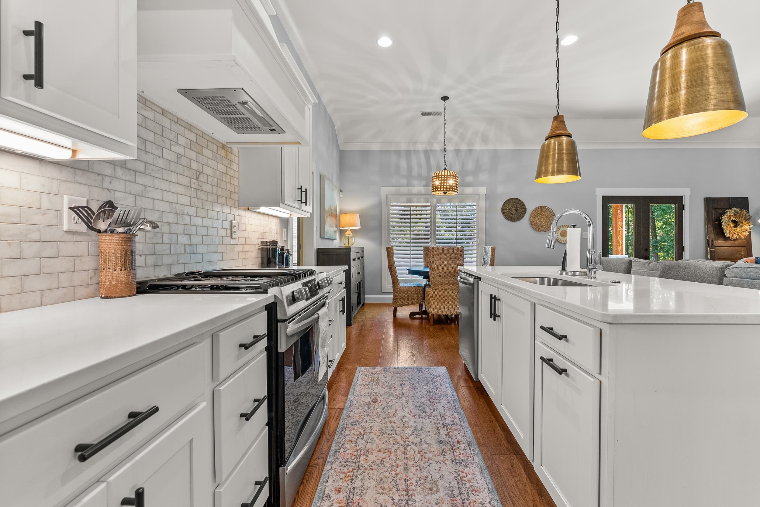 Kitchen with hanging light fixtures, white cabinetry, dark hardwood / wood-style floors, sink, and stainless steel appliances