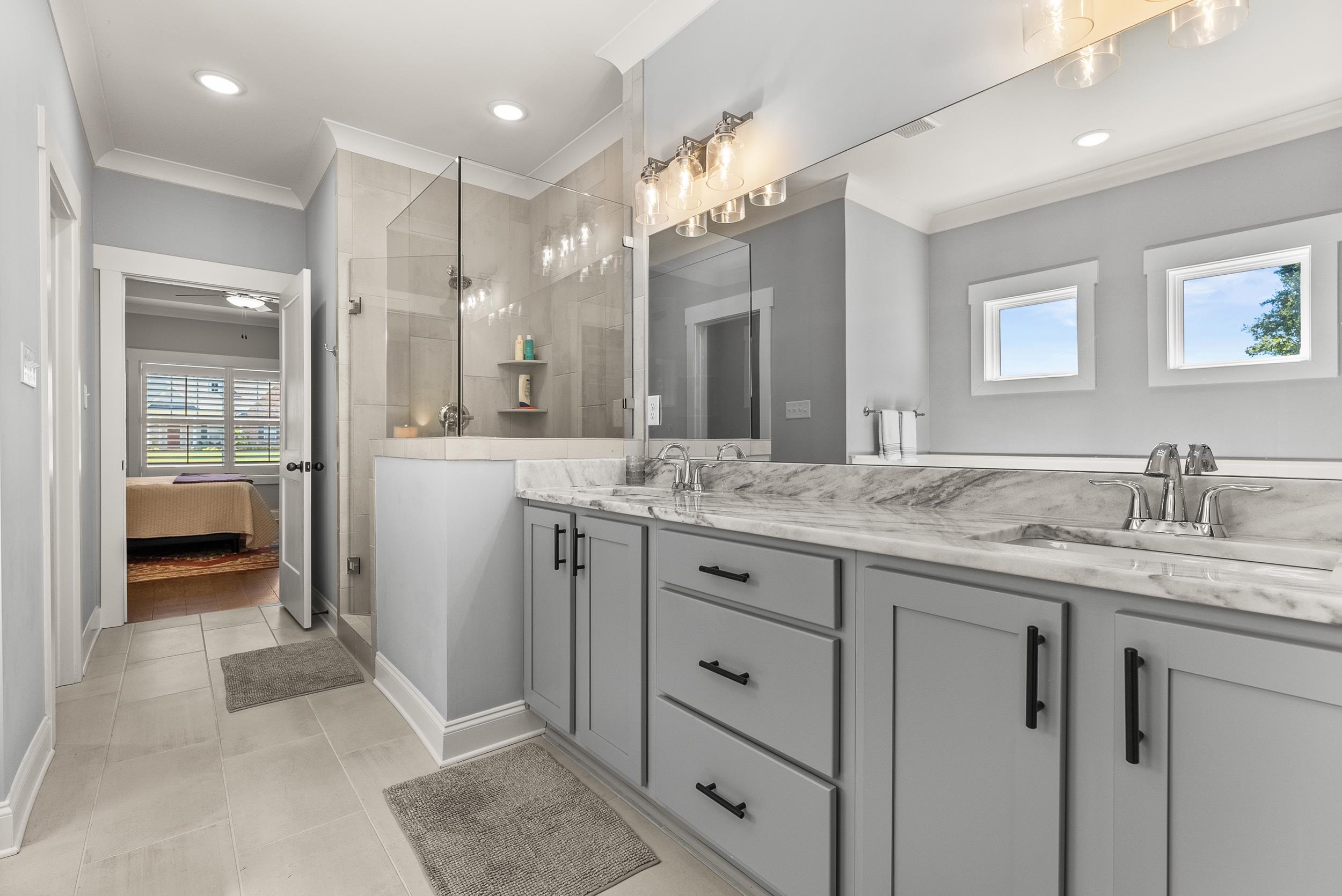 Bathroom featuring vanity, crown molding, tile patterned floors, and tiled shower