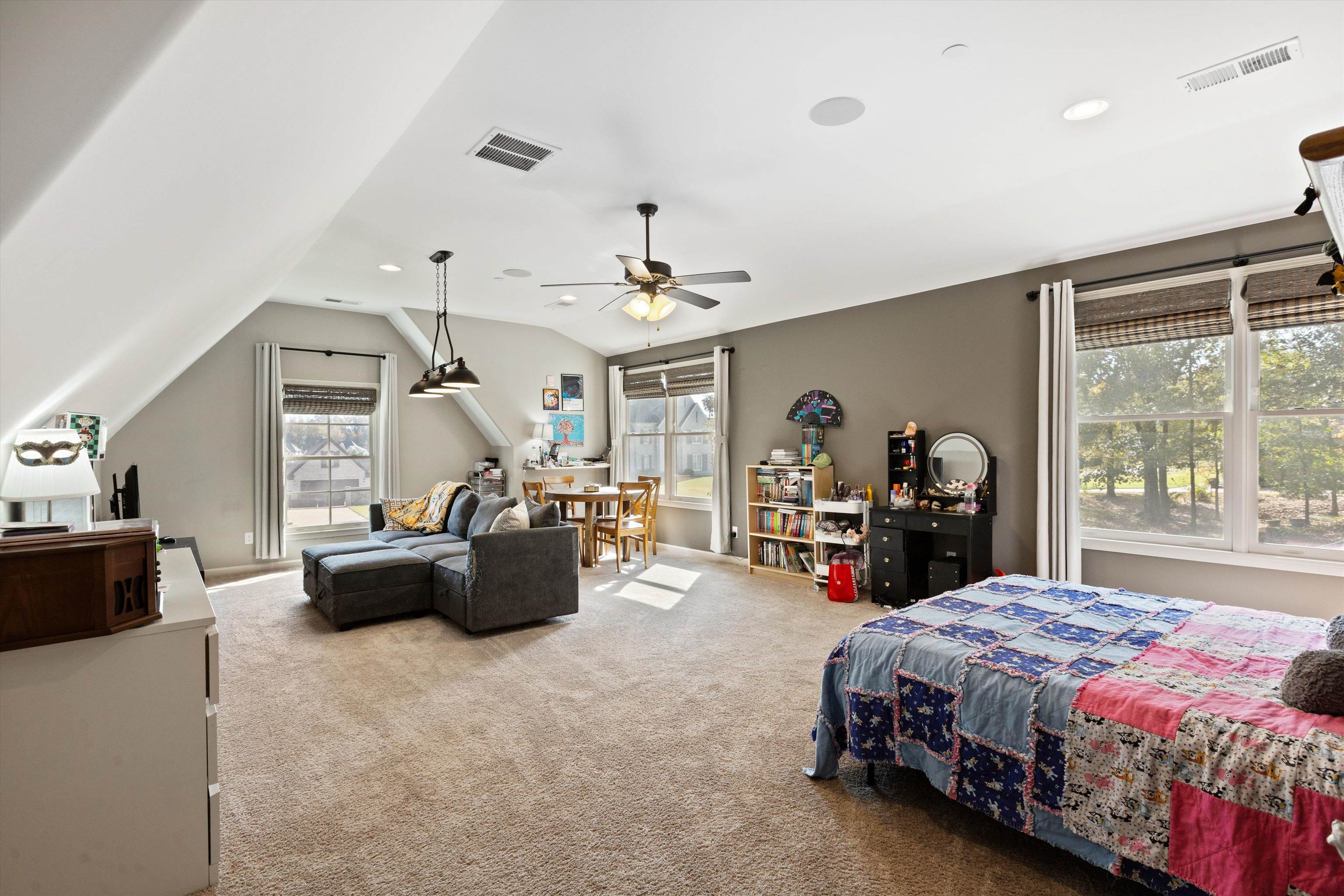 Carpeted bedroom featuring ceiling fan, lofted ceiling, and multiple windows