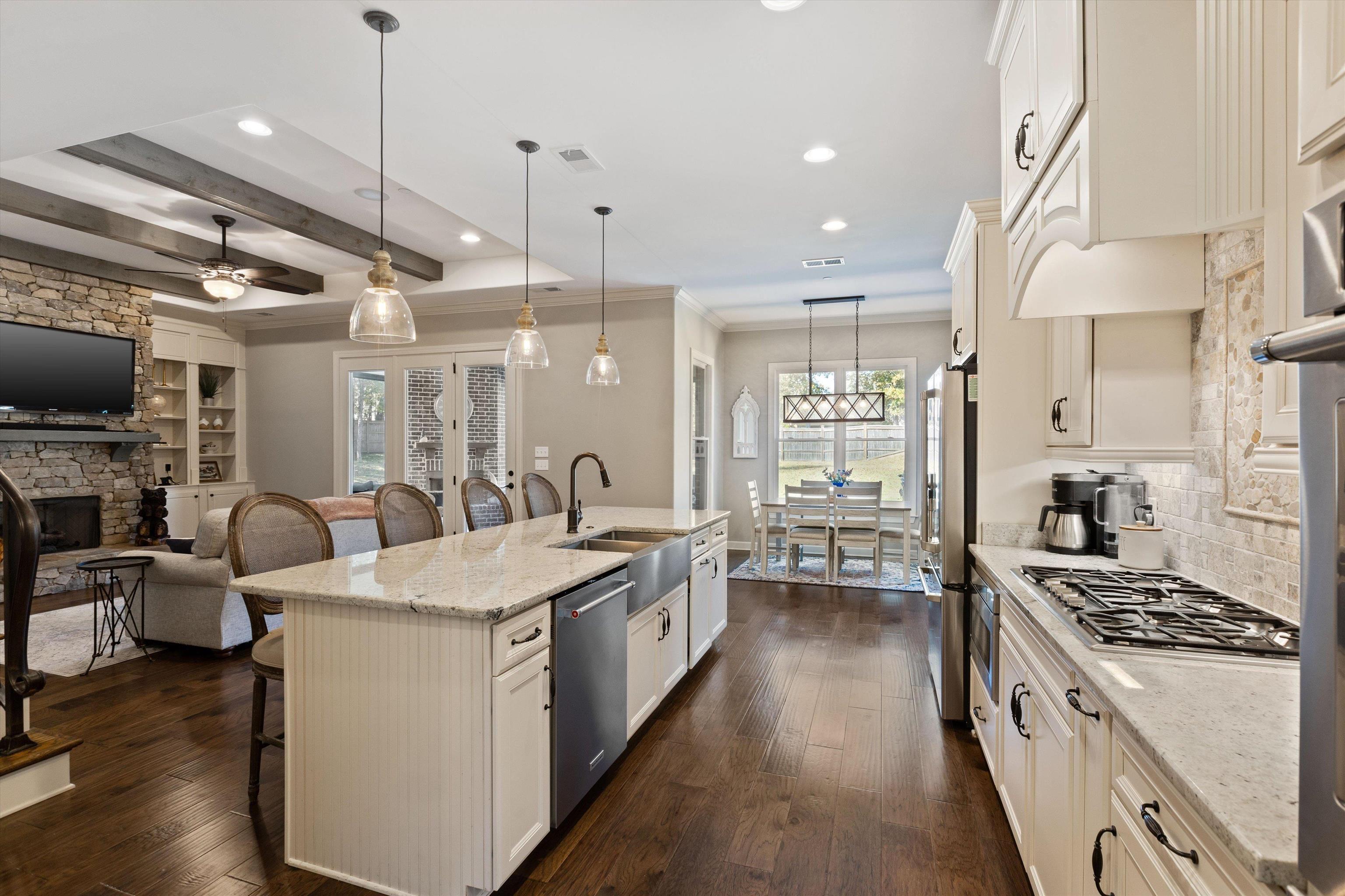 Kitchen featuring stainless steel appliances, light stone counters, a breakfast bar area, dark hardwood / wood-style floors, and a kitchen island with sink