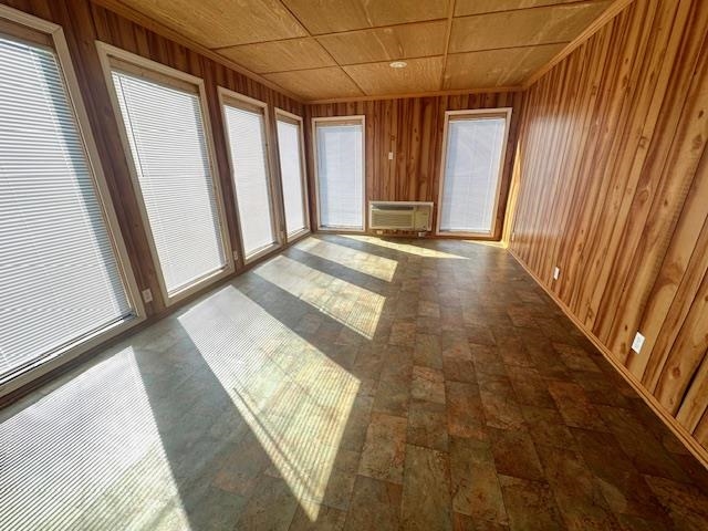 Unfurnished sunroom featuring wood ceiling and an AC wall unit