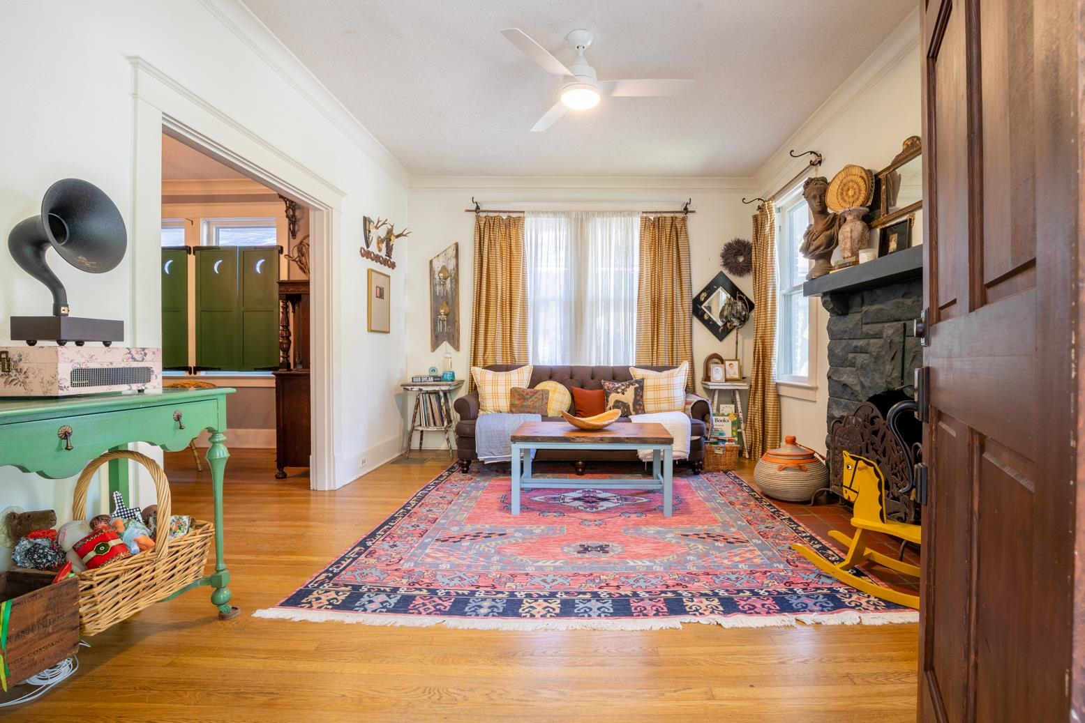 Living room featuring a fireplace, ornamental molding, light hardwood flooring, and ceiling fan