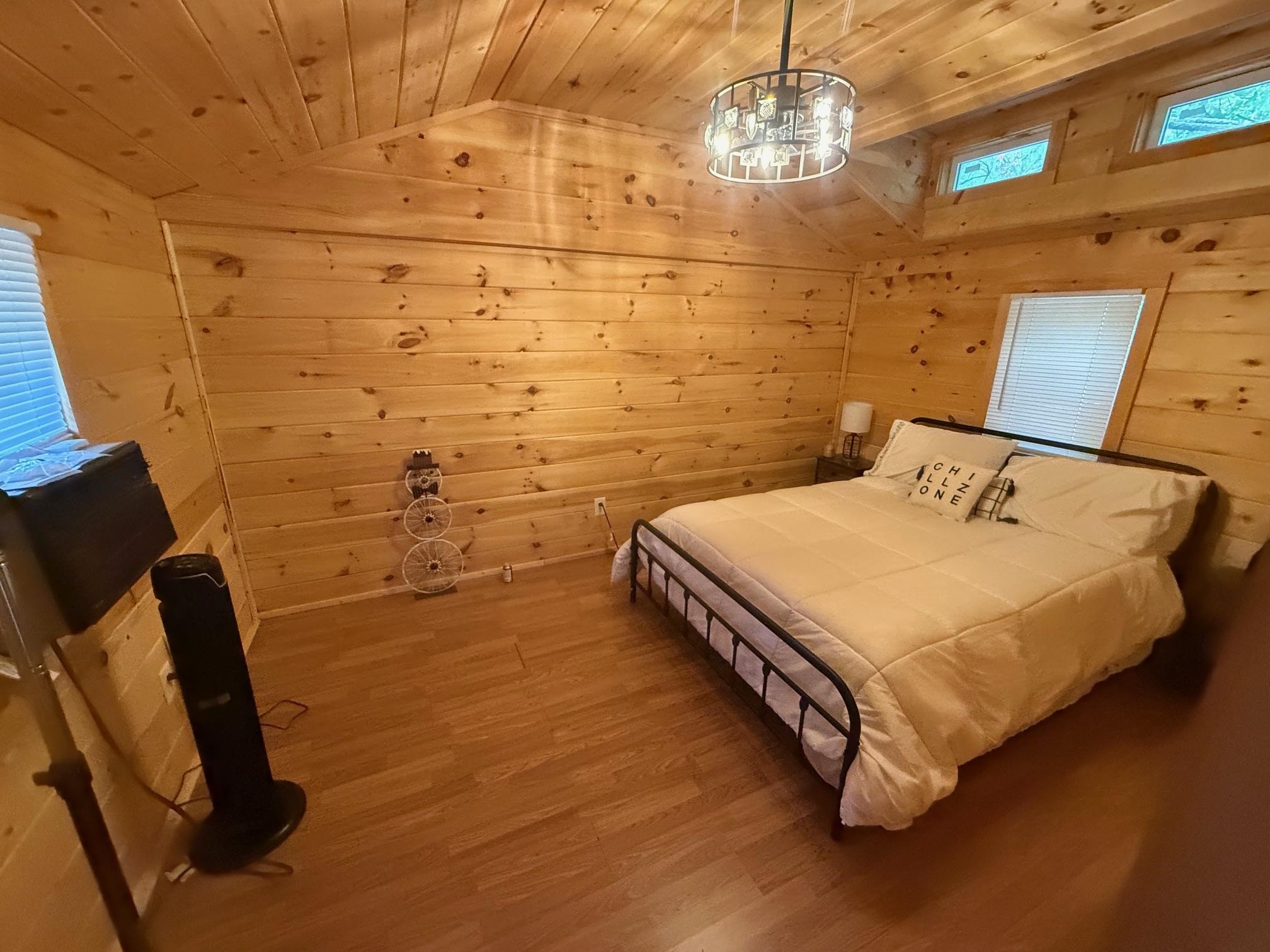 Bedroom featuring lofted ceiling, wood walls, wood ceiling, and light wood-type flooring