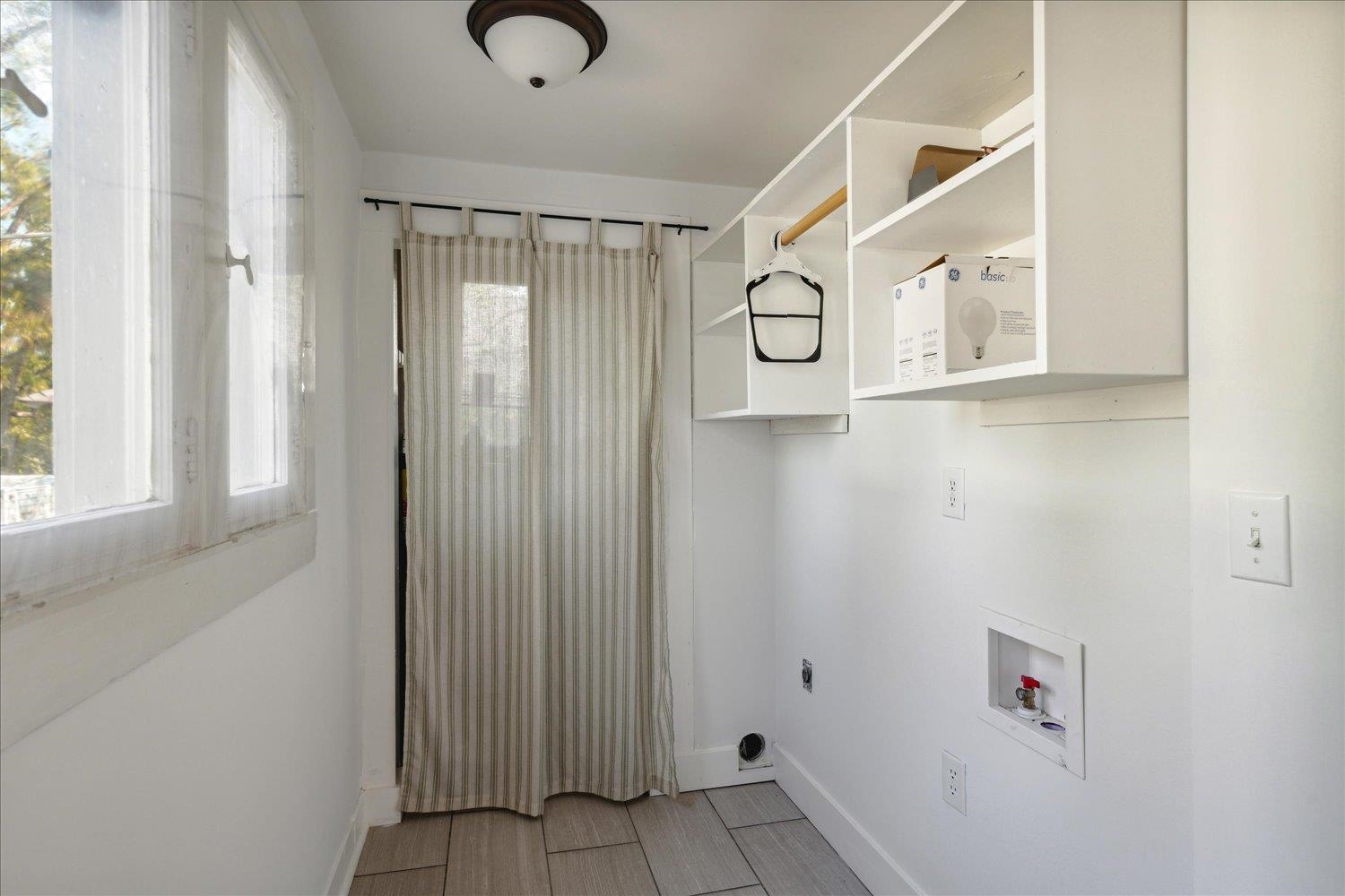 Washroom with hookup for an electric dryer, light hardwood / wood-style flooring, and hookup for a washing machine