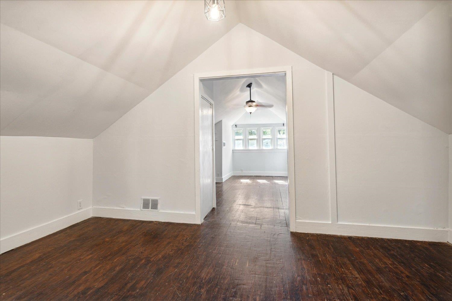 Bonus room with vaulted ceiling, dark hardwood / wood-style floors, and ceiling fan