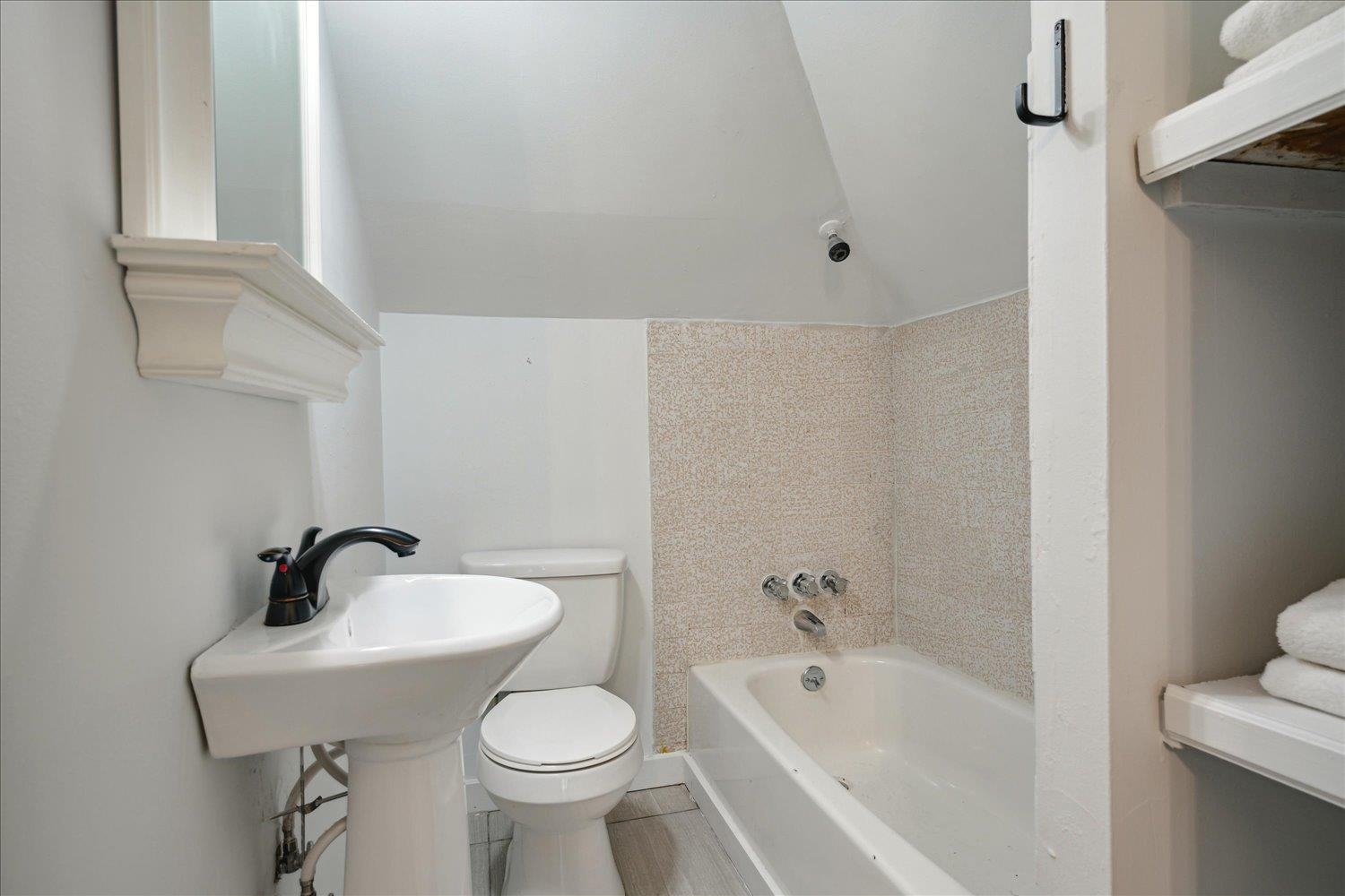 Bathroom with toilet, vaulted ceiling, and tile patterned flooring