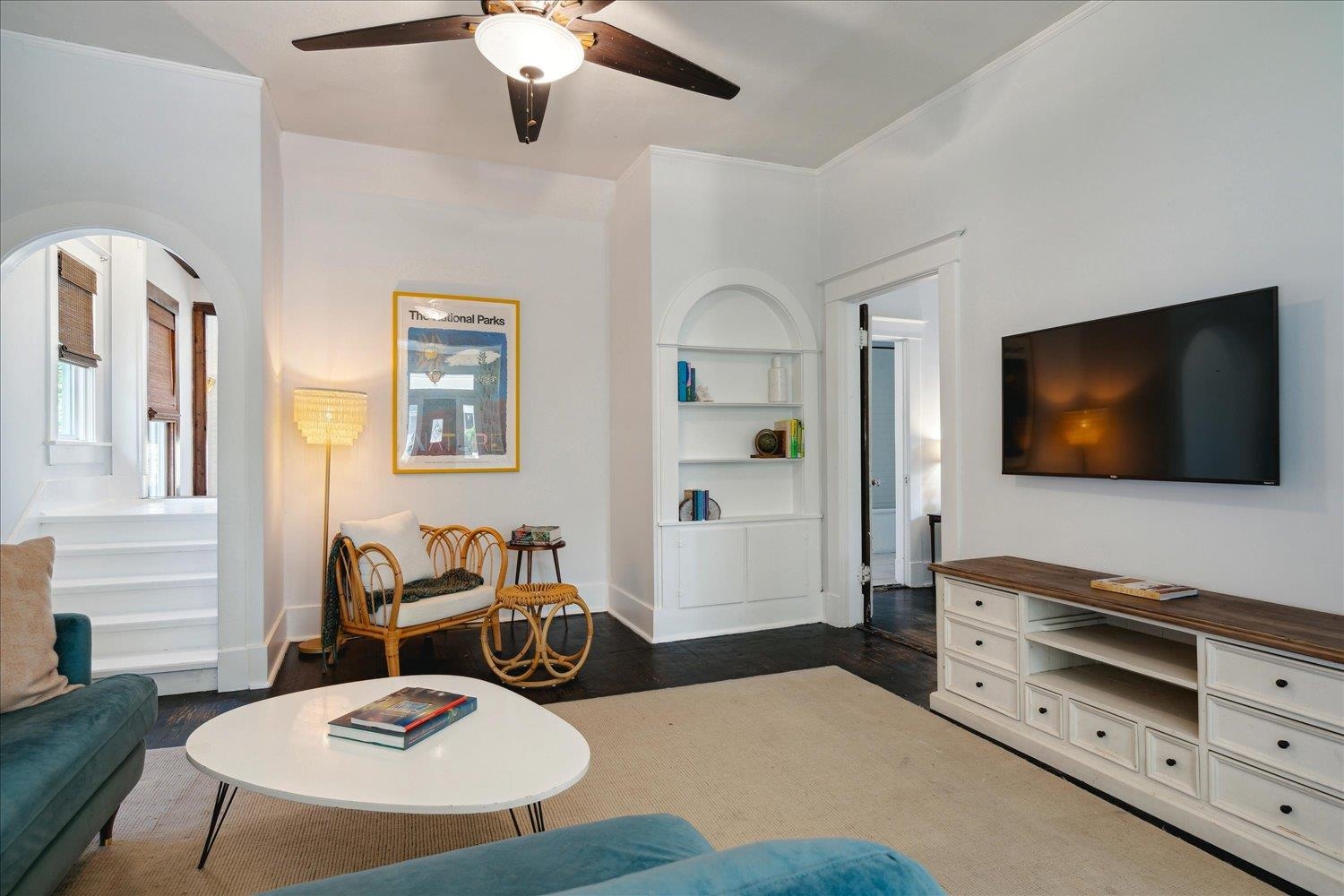 Living room featuring ornamental molding, dark wood-type flooring, built in shelves, and ceiling fan