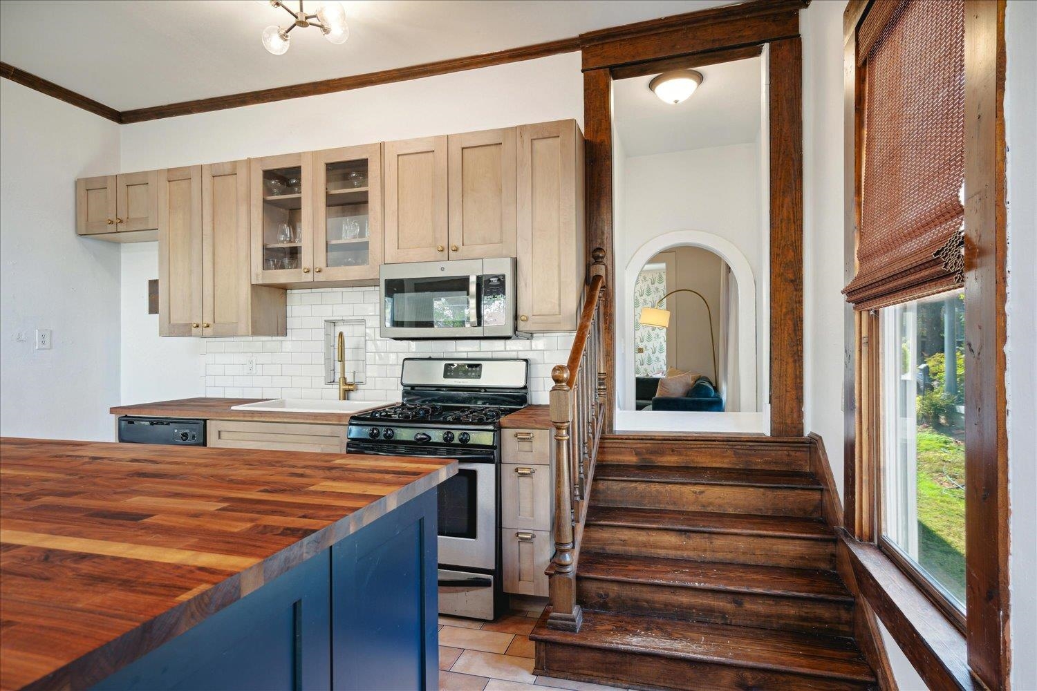 Kitchen featuring appliances with stainless steel finishes, decorative backsplash, a healthy amount of sunlight, and butcher block countertops