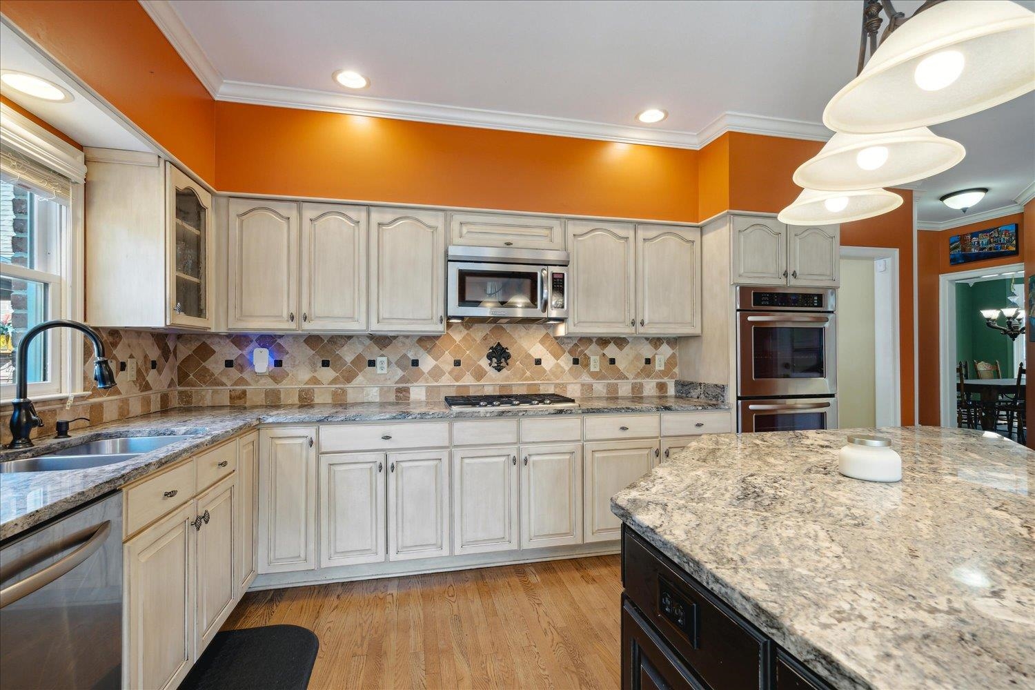 Kitchen featuring appliances with stainless steel finishes, crown molding, sink, and light wood-type flooring