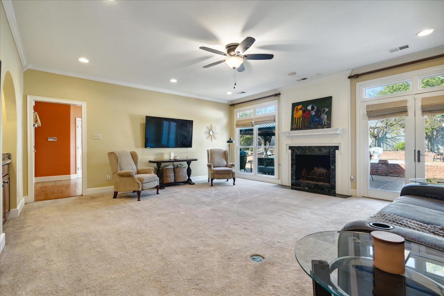 Carpeted living room with a premium fireplace, ornamental molding, and ceiling fan