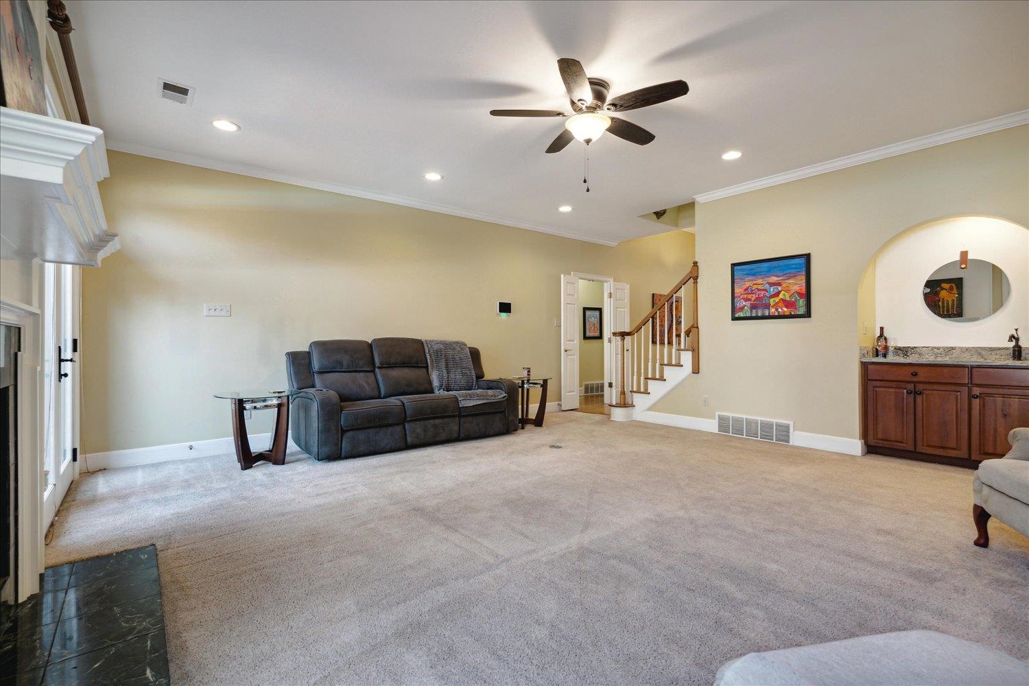 Living room featuring ceiling fan, ornamental molding, and light colored carpet