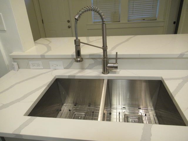 Room details featuring light stone countertops, sink, and green cabinetry