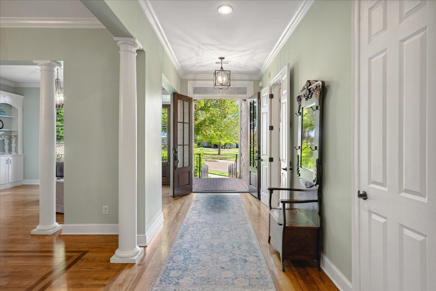 Entryway with ornamental molding, hardwood / wood-style floors, and a notable chandelier