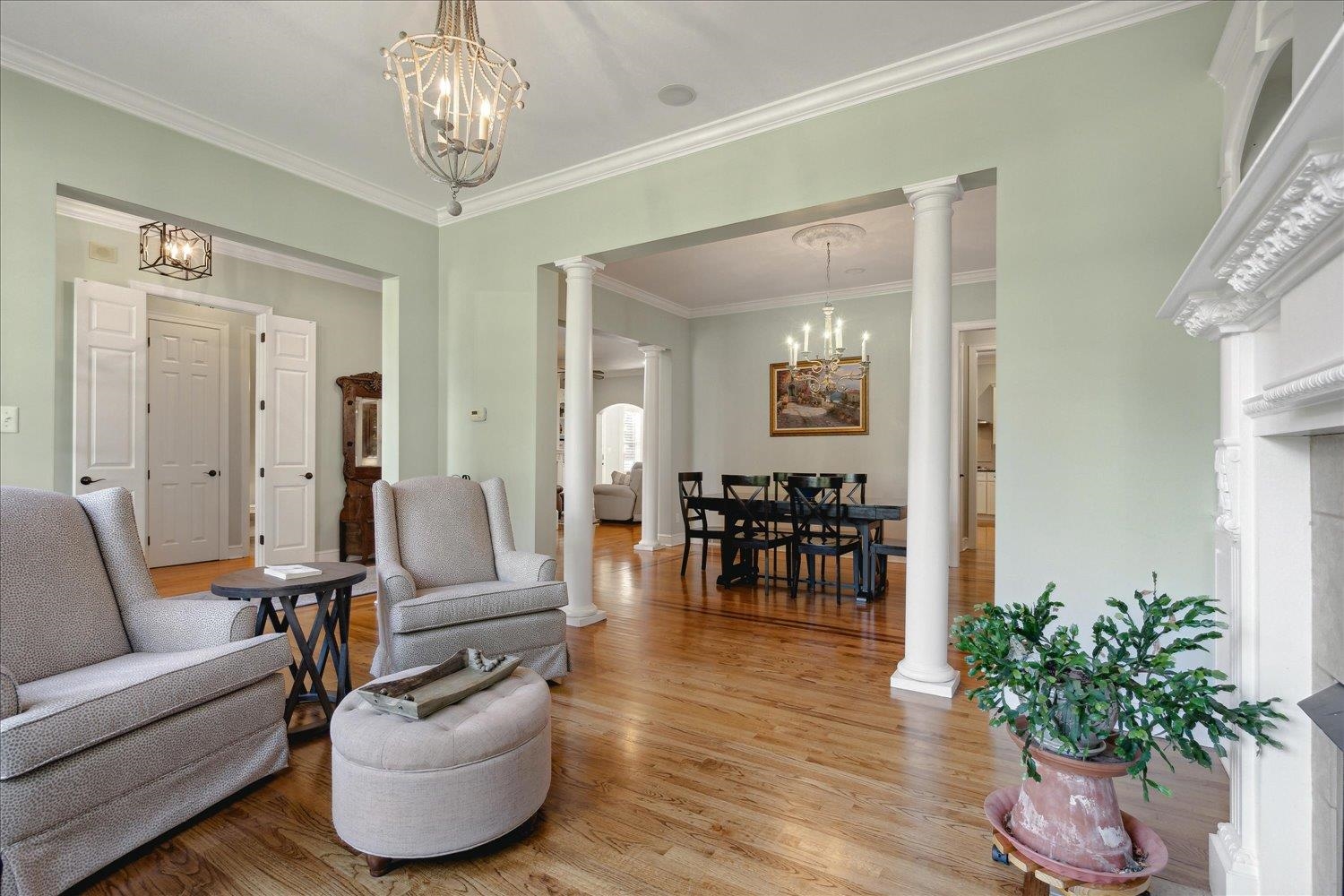 Living room featuring decorative columns, ornamental molding, light hardwood / wood-style flooring, and plenty of natural light