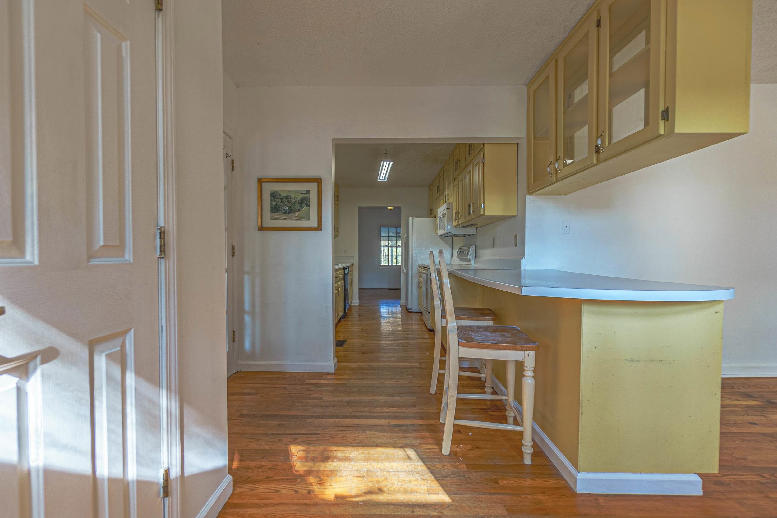 Kitchen featuring a kitchen breakfast bar, dark wood-type flooring, and white refrigerator