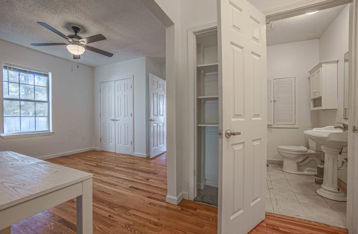 Bathroom featuring toilet, hardwood / wood-style floors, a textured ceiling, and ceiling fan