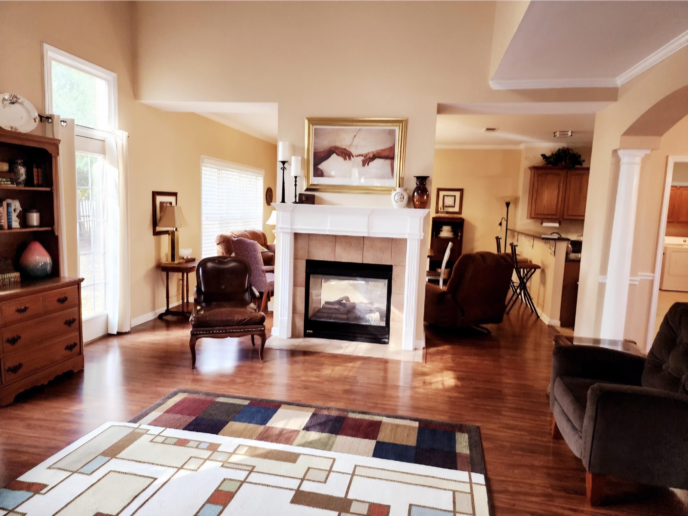 Living room featuring washer / clothes dryer, a tiled fireplace, decorative columns, ornamental molding, and dark wood-type flooring