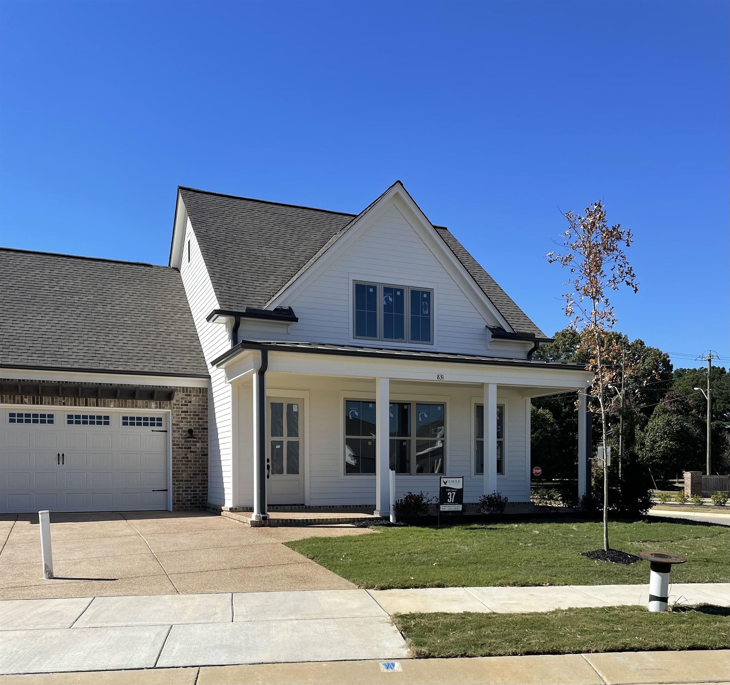 View of front of house featuring a front lawn, covered porch, and a garage