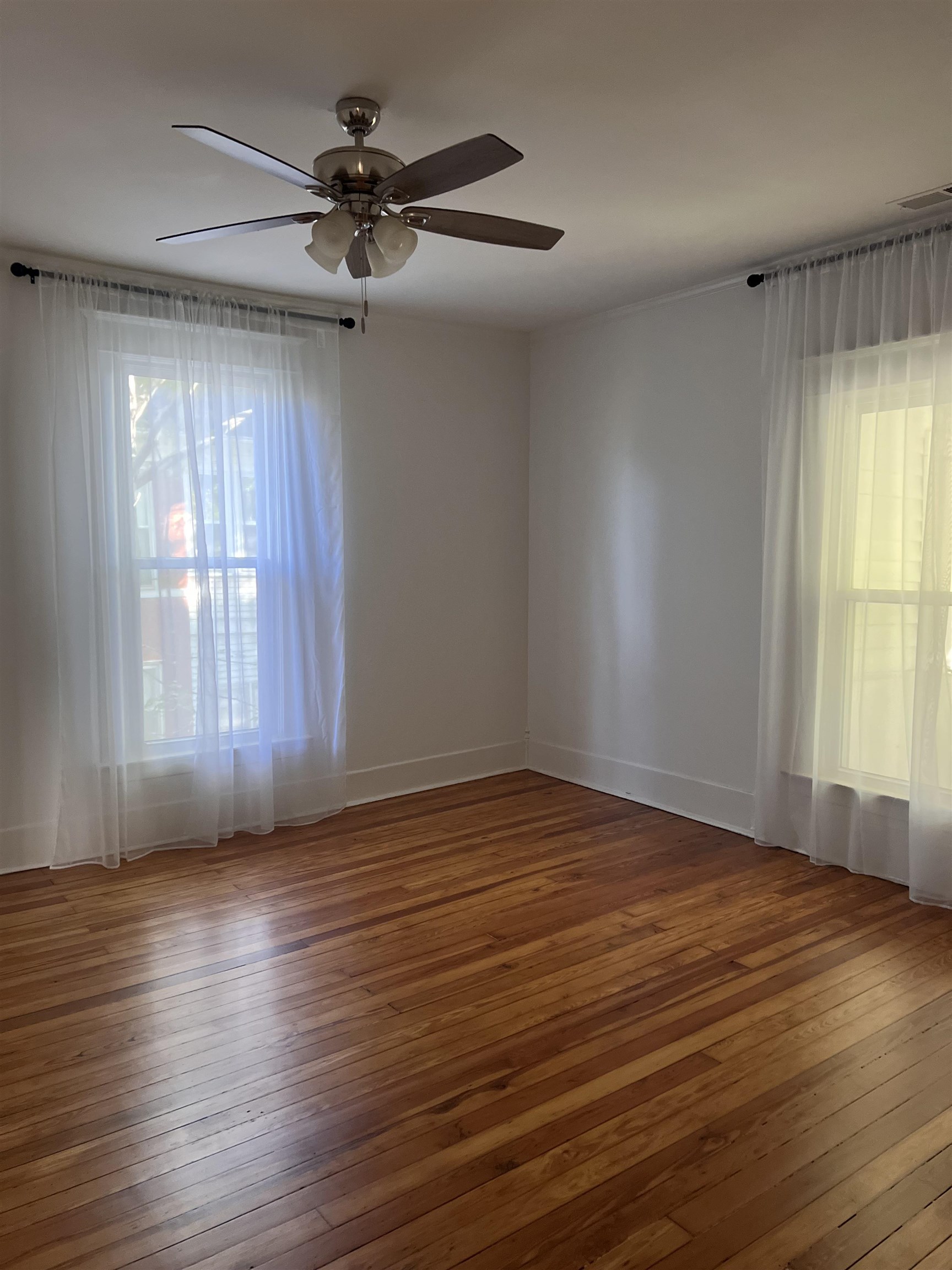 Empty room with hardwood / wood-style flooring and ceiling fan