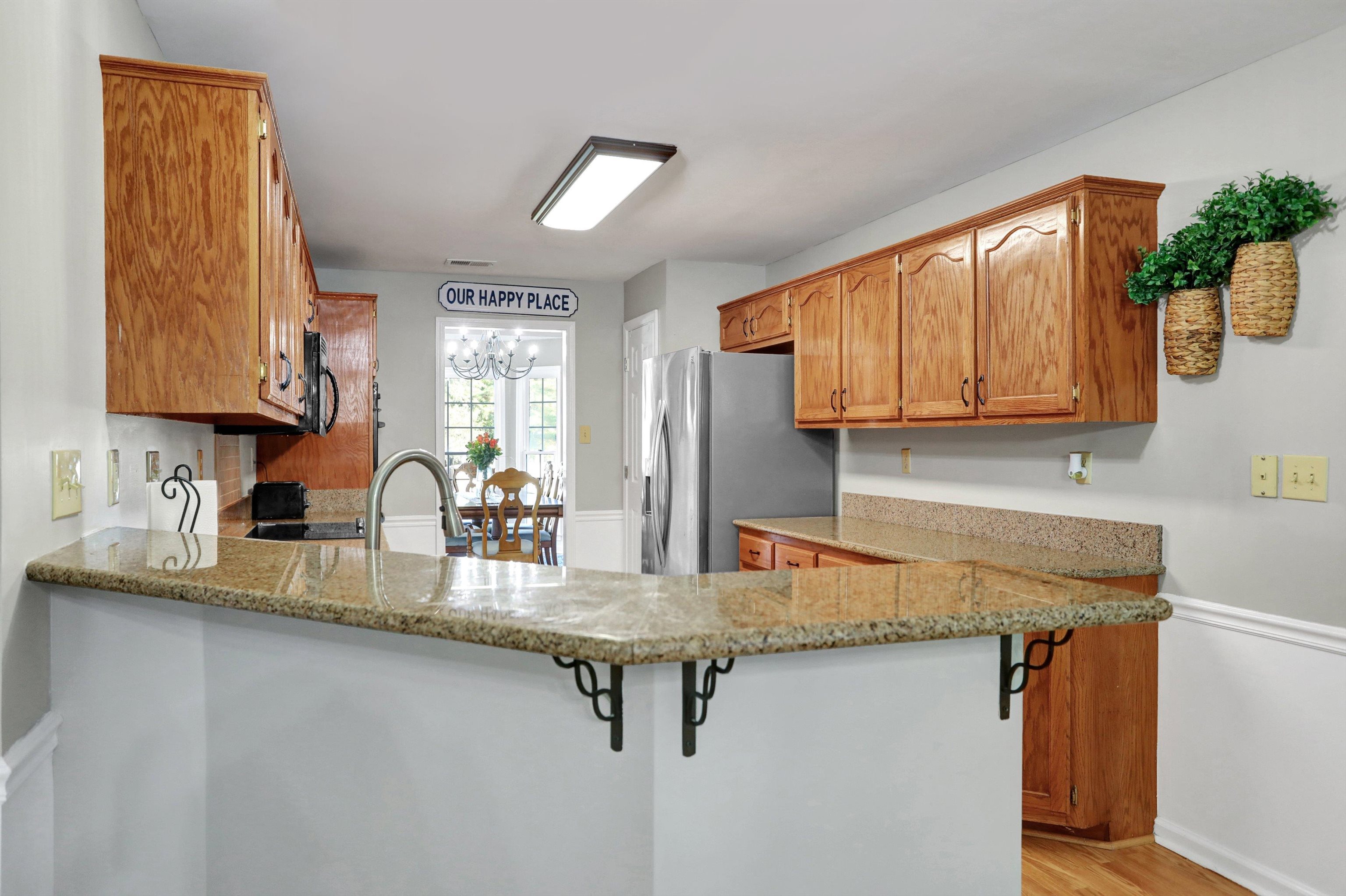 Kitchen featuring light wood-type flooring, a notable chandelier, light stone countertops, and kitchen peninsula