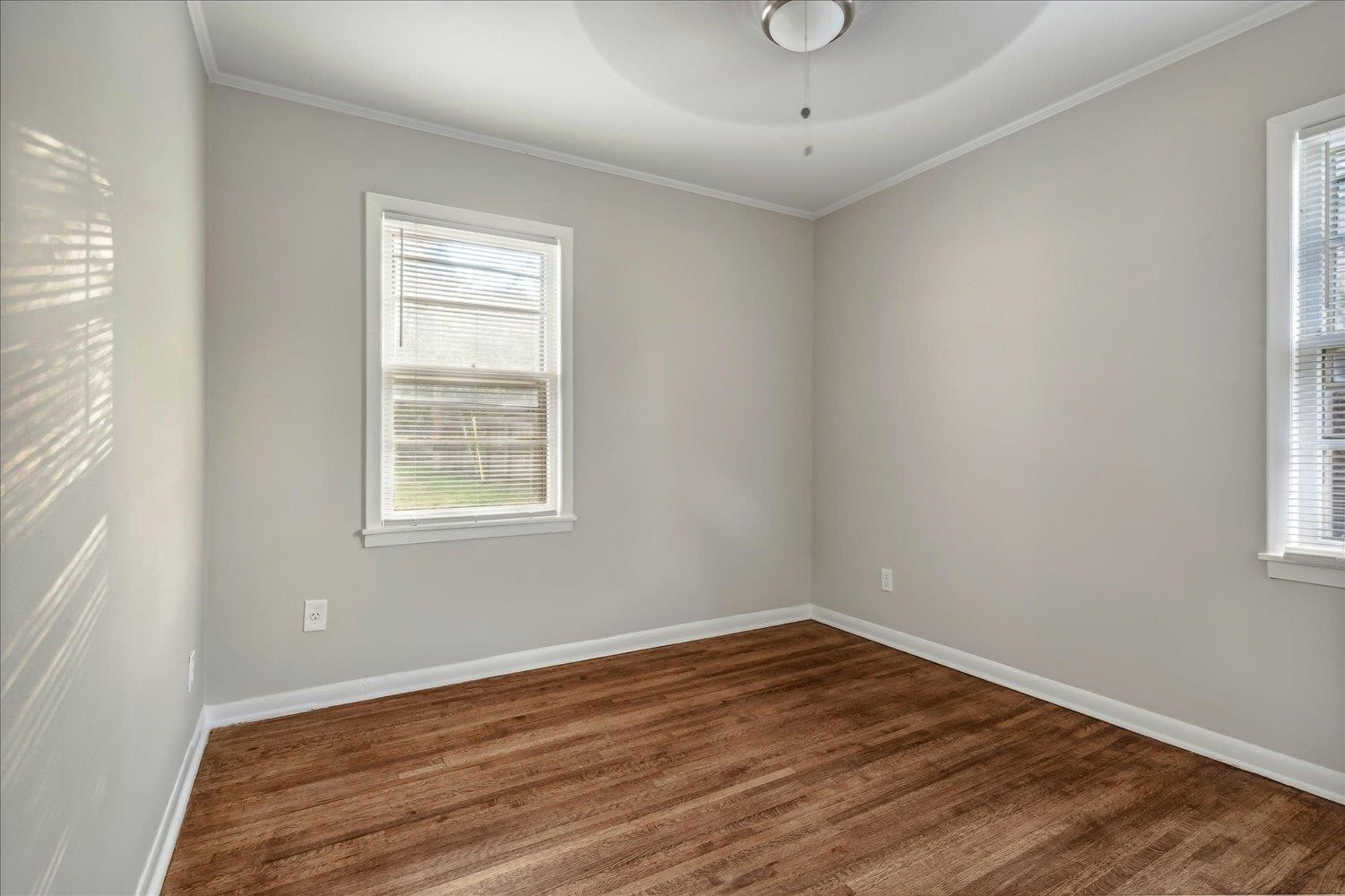 Spare room with ceiling fan, a healthy amount of sunlight, and dark hardwood / wood-style floors