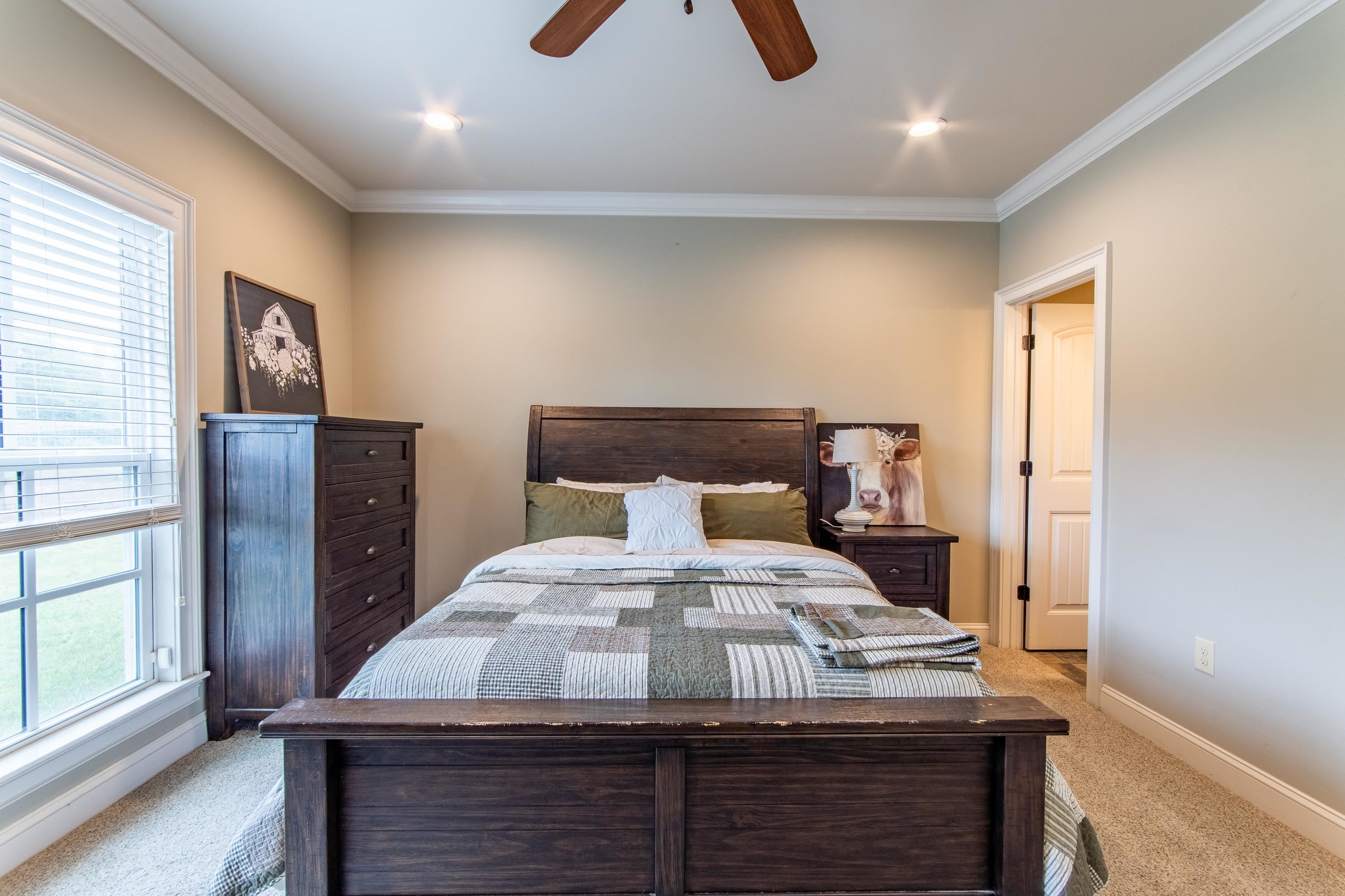 Bedroom with light carpet, ornamental molding, and ceiling fan