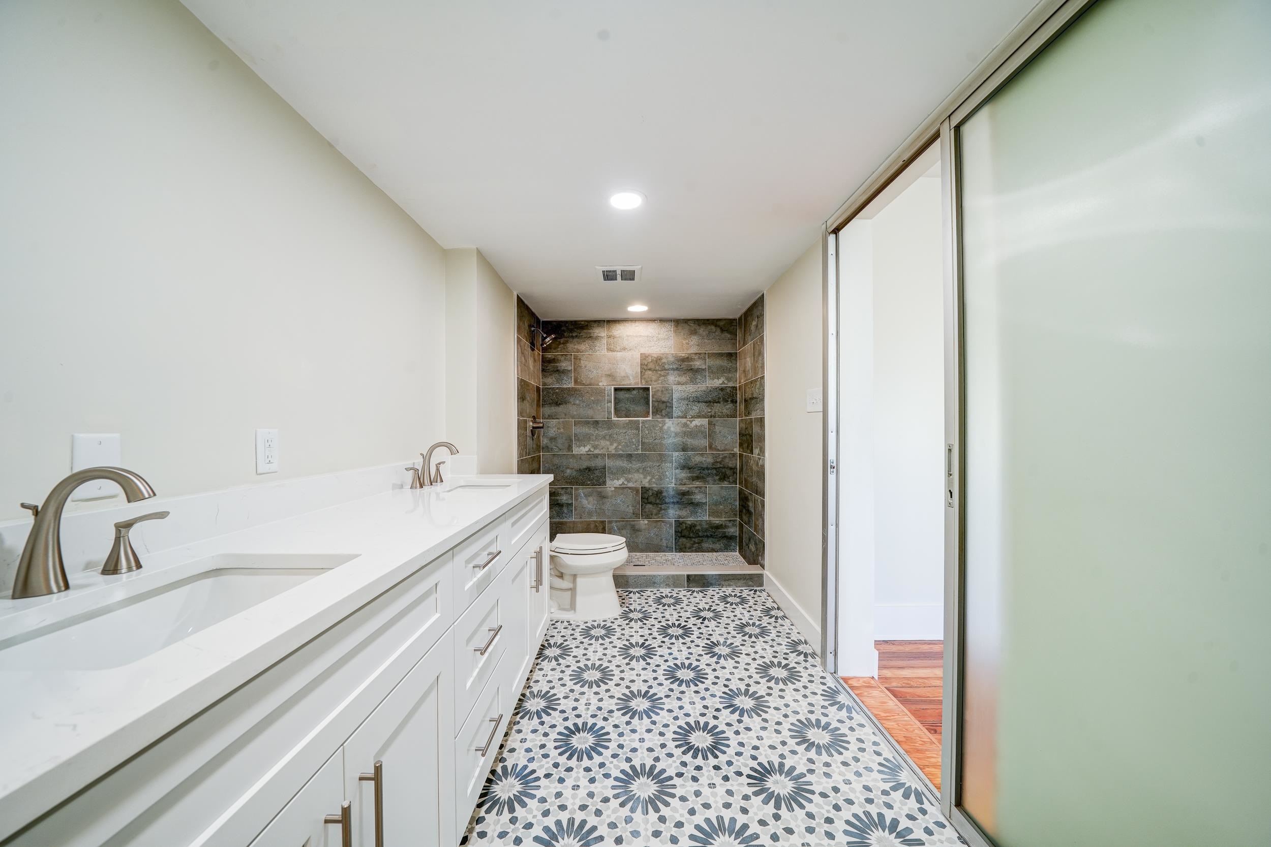 Bathroom featuring a tile shower, toilet, and vanity