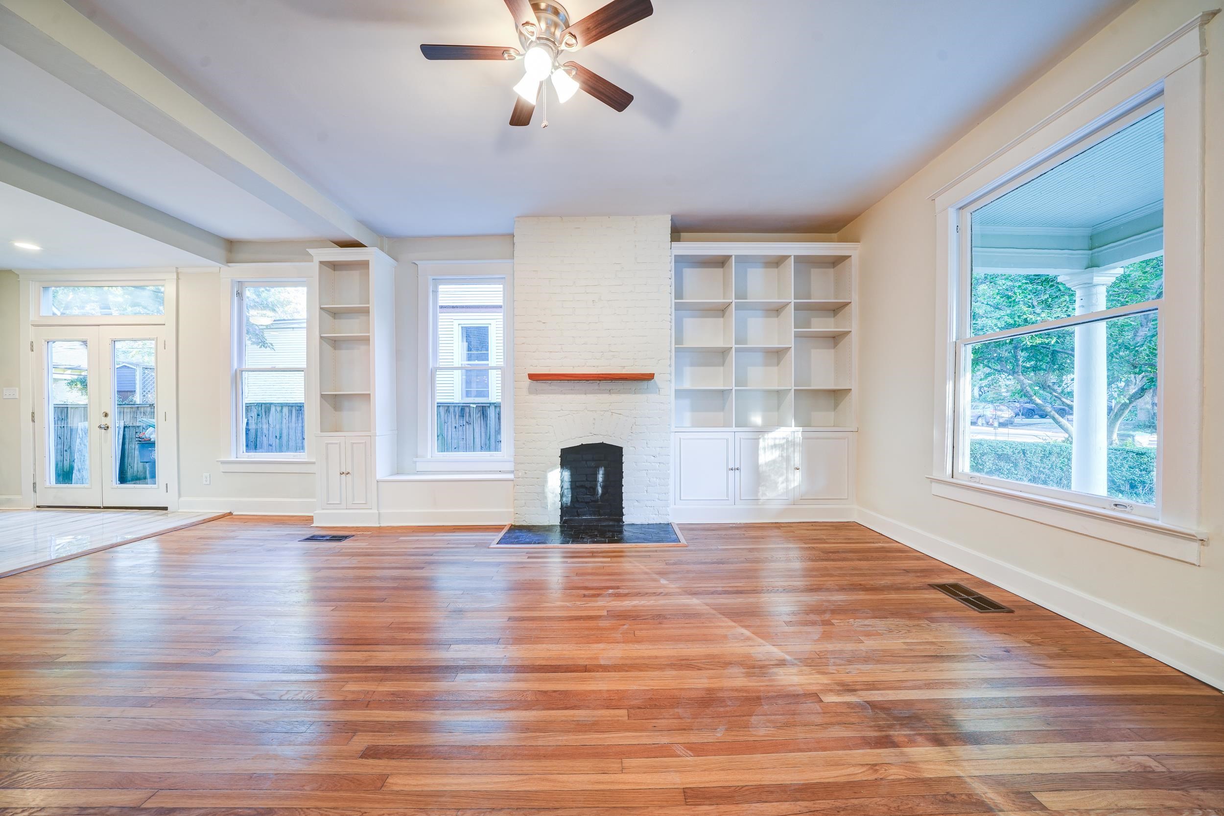 Unfurnished living room with a large fireplace, wood-type flooring, and built in features