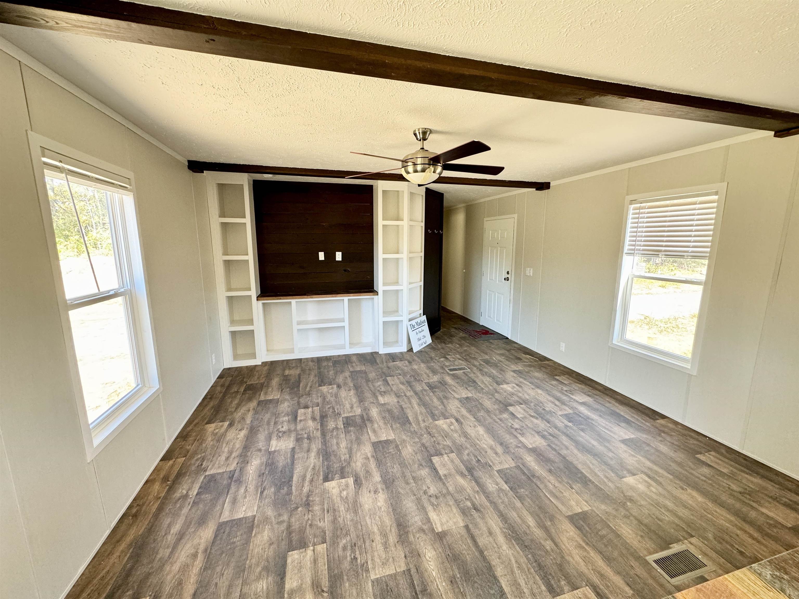 Unfurnished living room with crown molding, ceiling fan, a textured ceiling, and dark hardwood / wood-style flooring