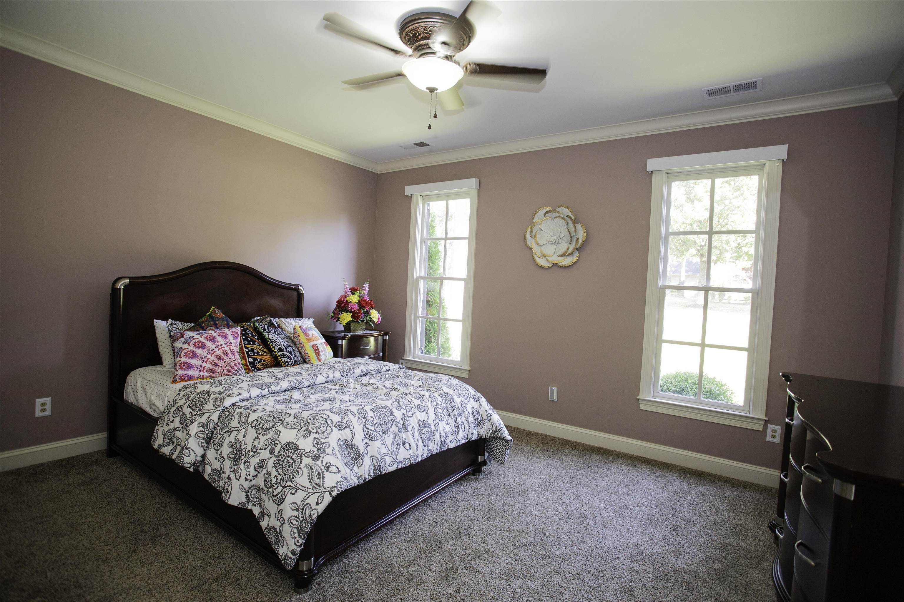 Carpeted bedroom with ceiling fan and crown molding