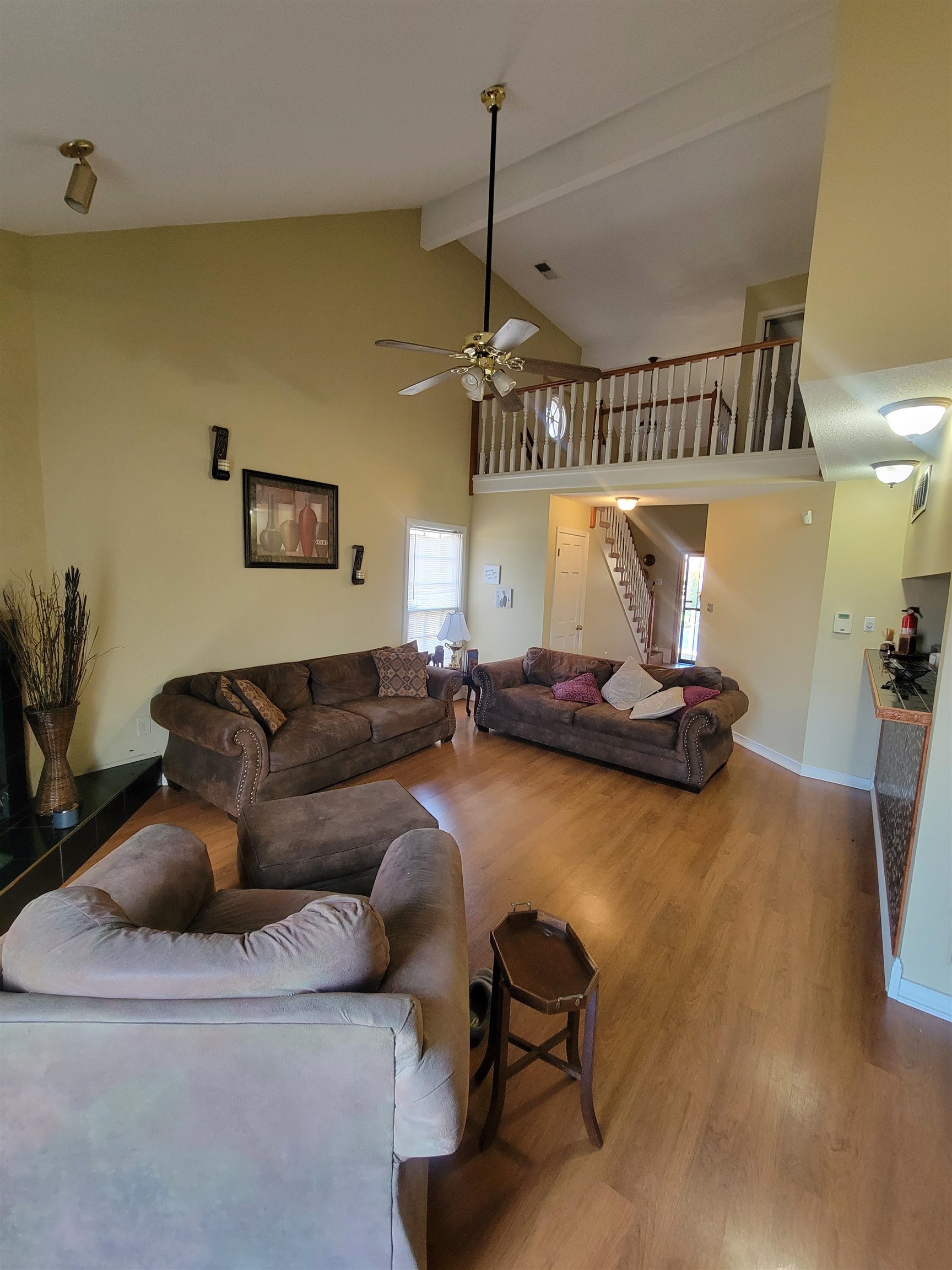 Living room featuring beamed ceiling, high vaulted ceiling, light wood-type flooring, and ceiling fan